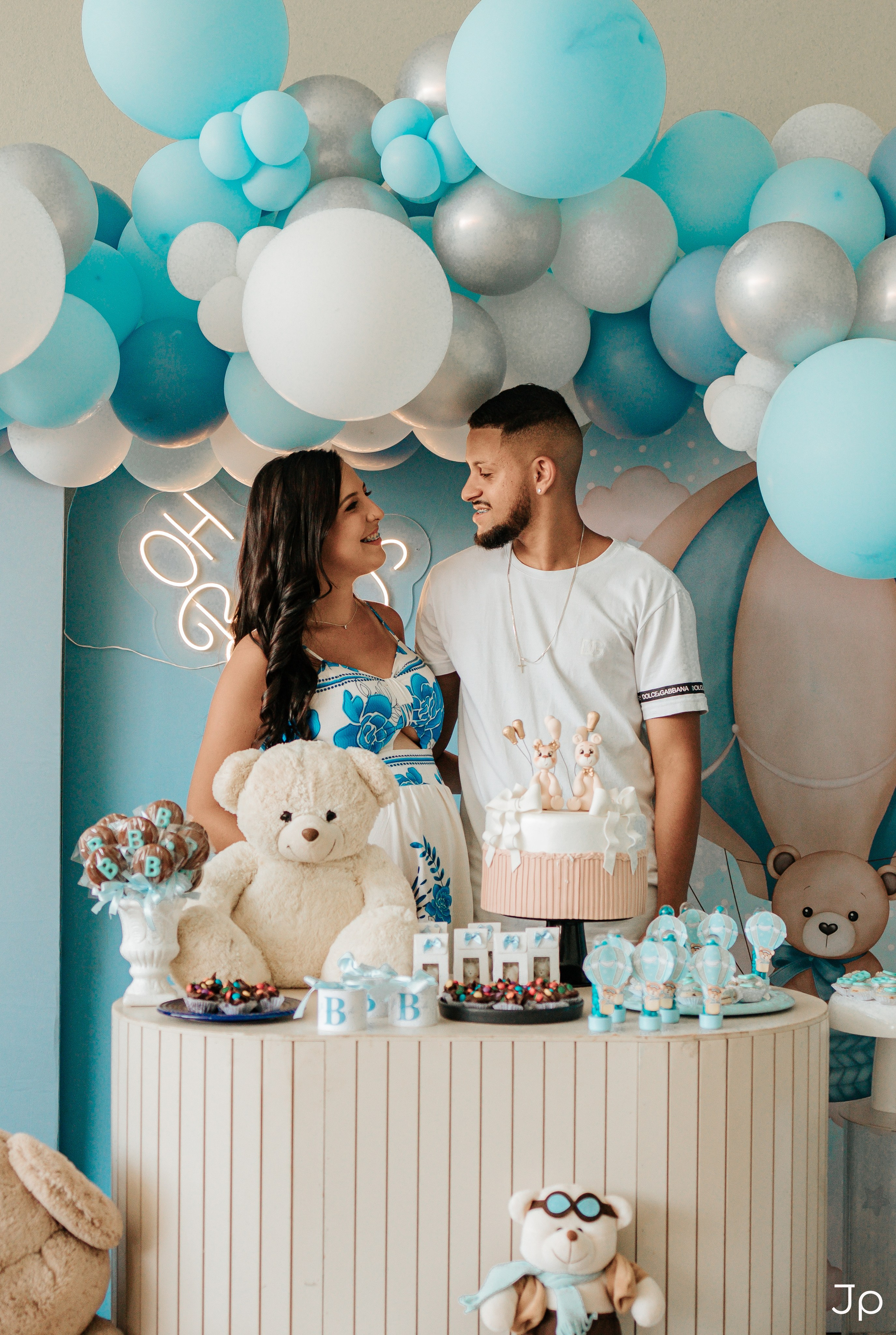 Casal interage sorrindo diante da mesa decorada do chá de bebê em Barra Bonita.