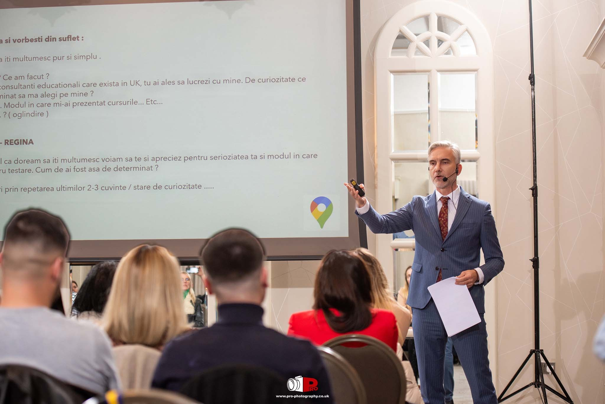 A workshop speaker engages with participants seated in a conference room with attentive listeners.