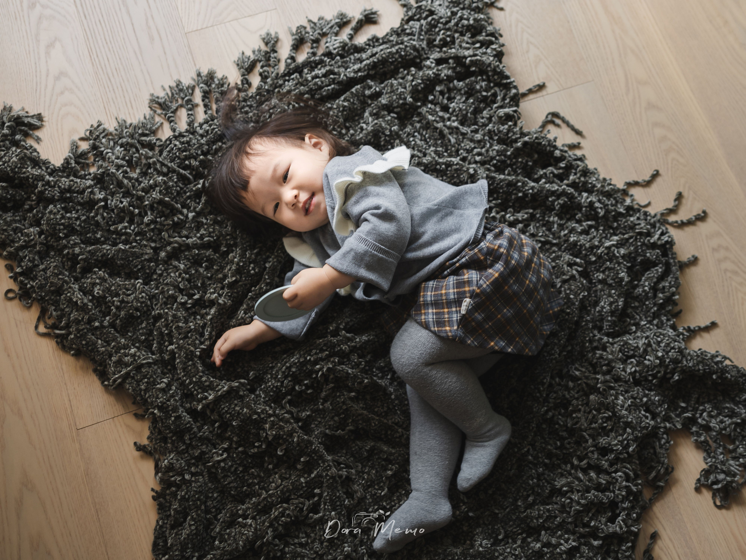 Top-down view of a toddler lying peacefully on a textured rug, quiet moment during a Shanghai family lifestyle photography session.