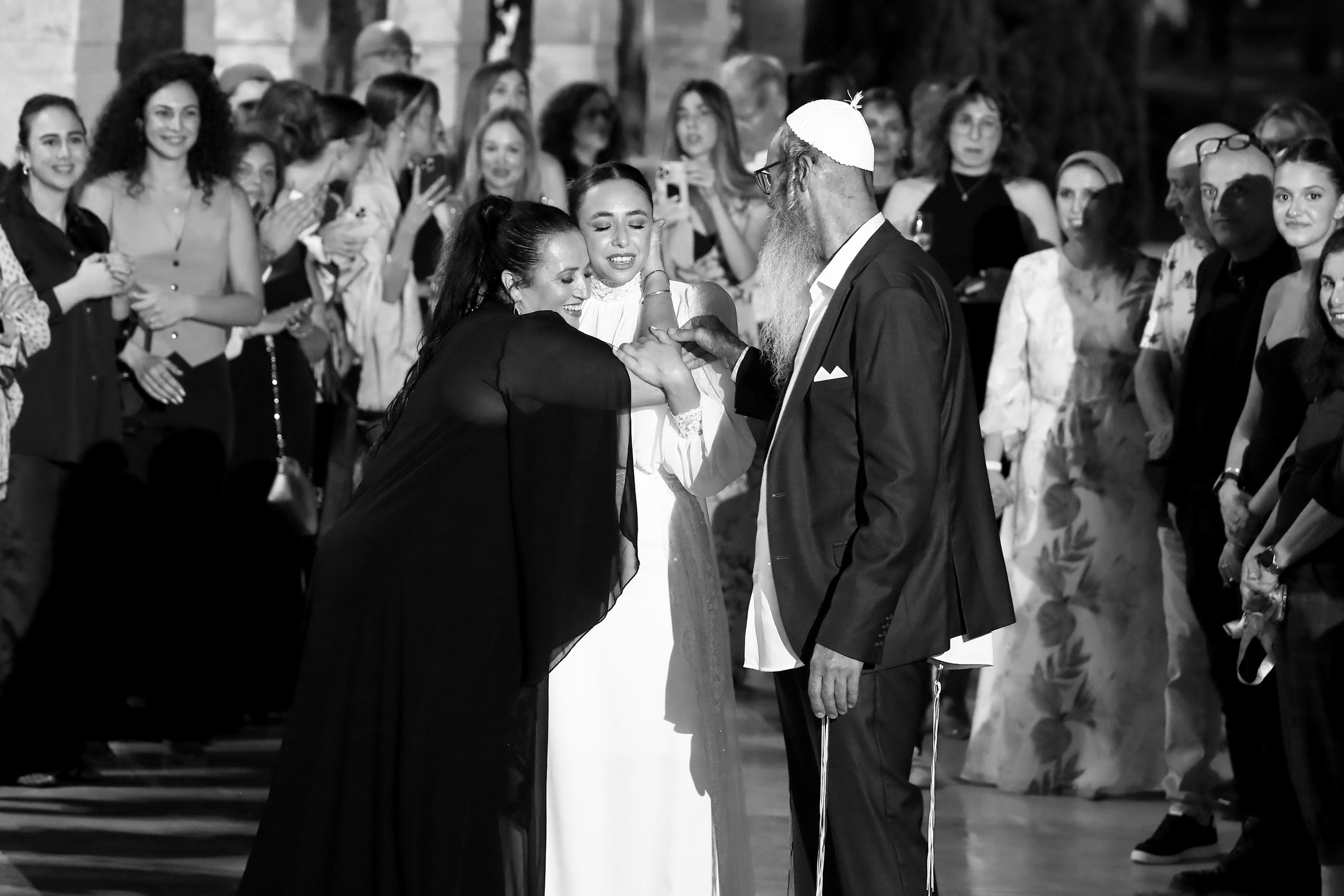 This heartfelt moment captures the bride’s parents tenderly embracing and blessing their daughter before she steps under the chuppah. Love, emotion, and tradition intertwine in this beautiful scene.