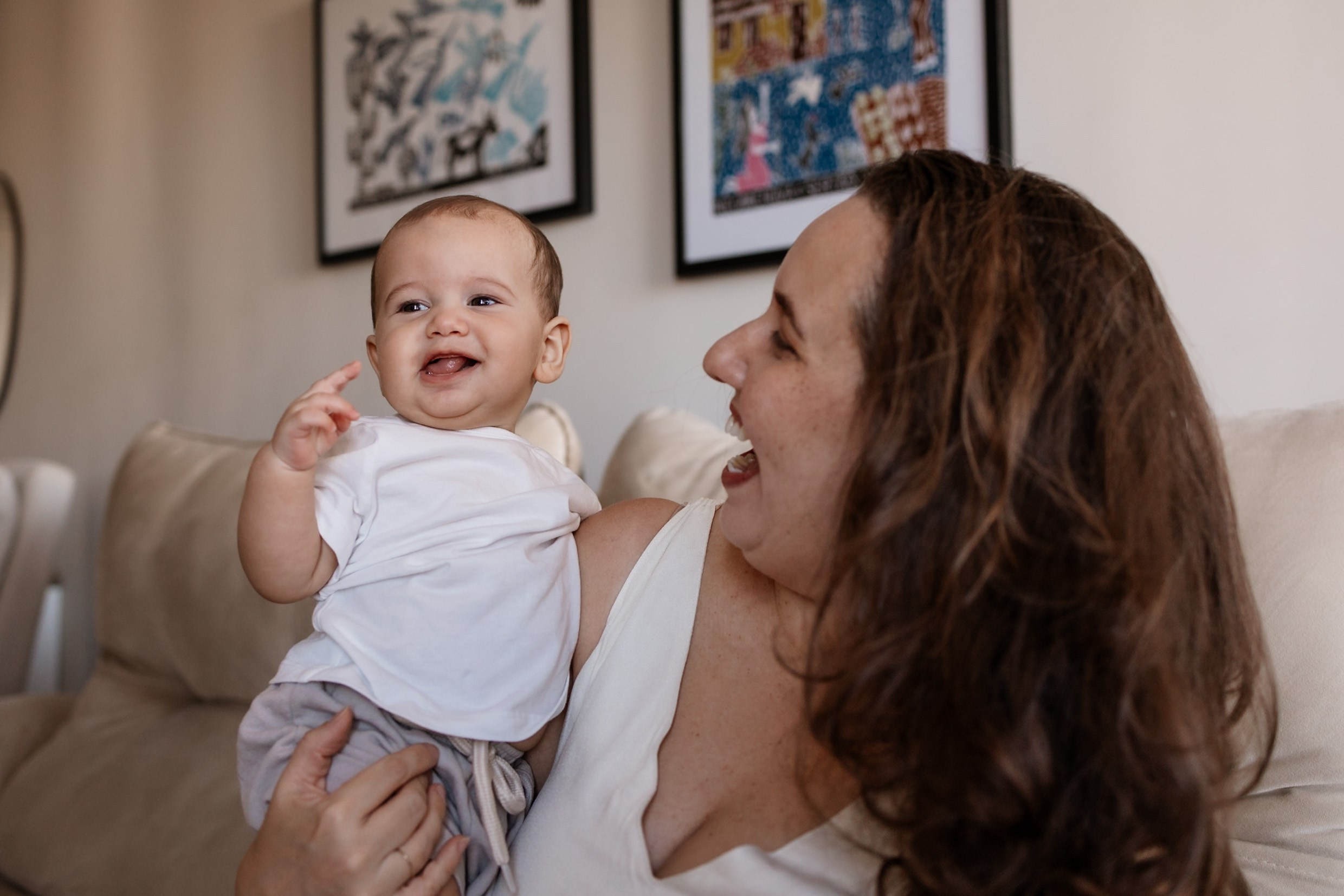 Bebê recebe carinho da mãe durante ensaio família em casa.
