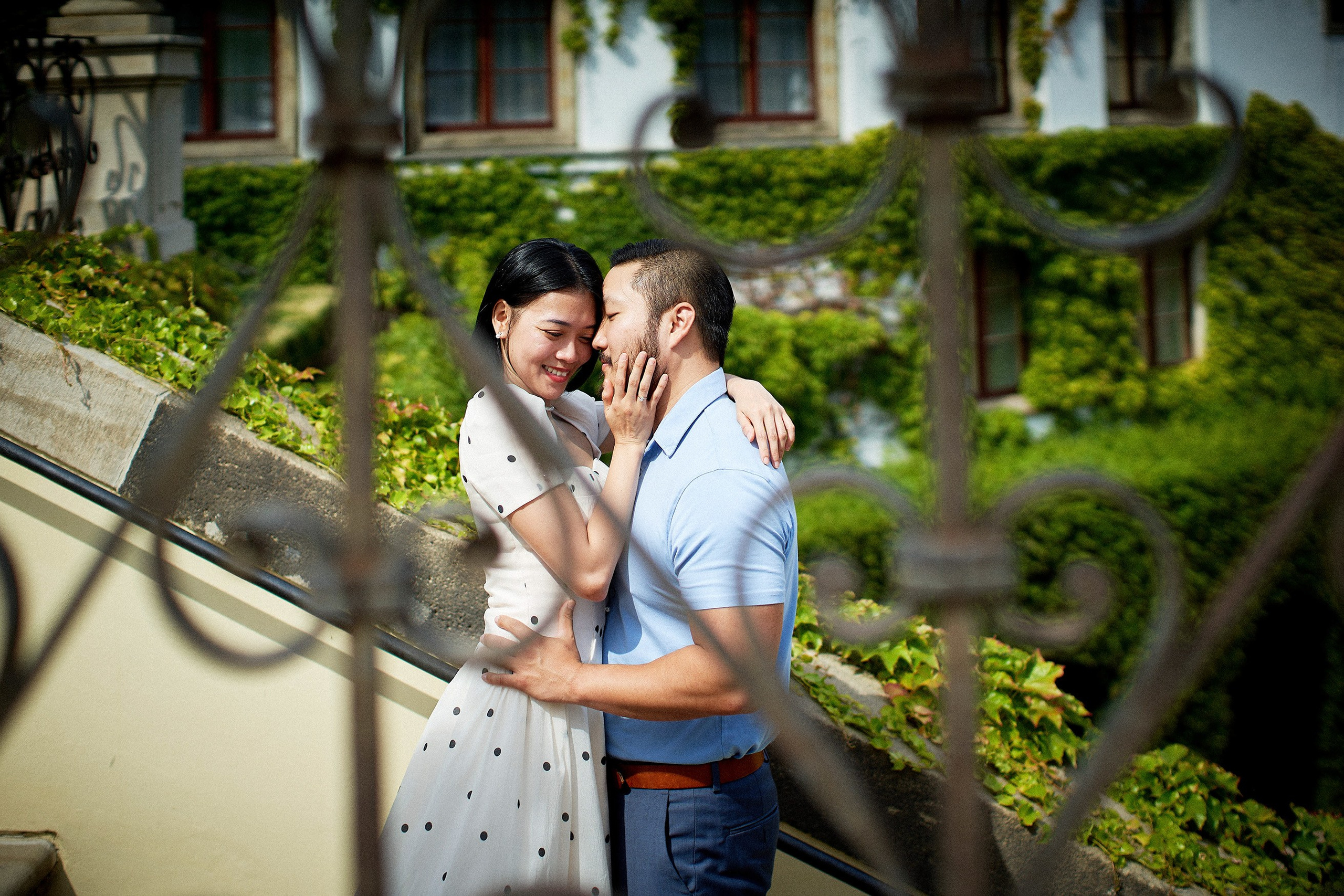 Woman lovingly stroking her partner's face amid lush vegetation in Vrtba Garden engagement shoot.