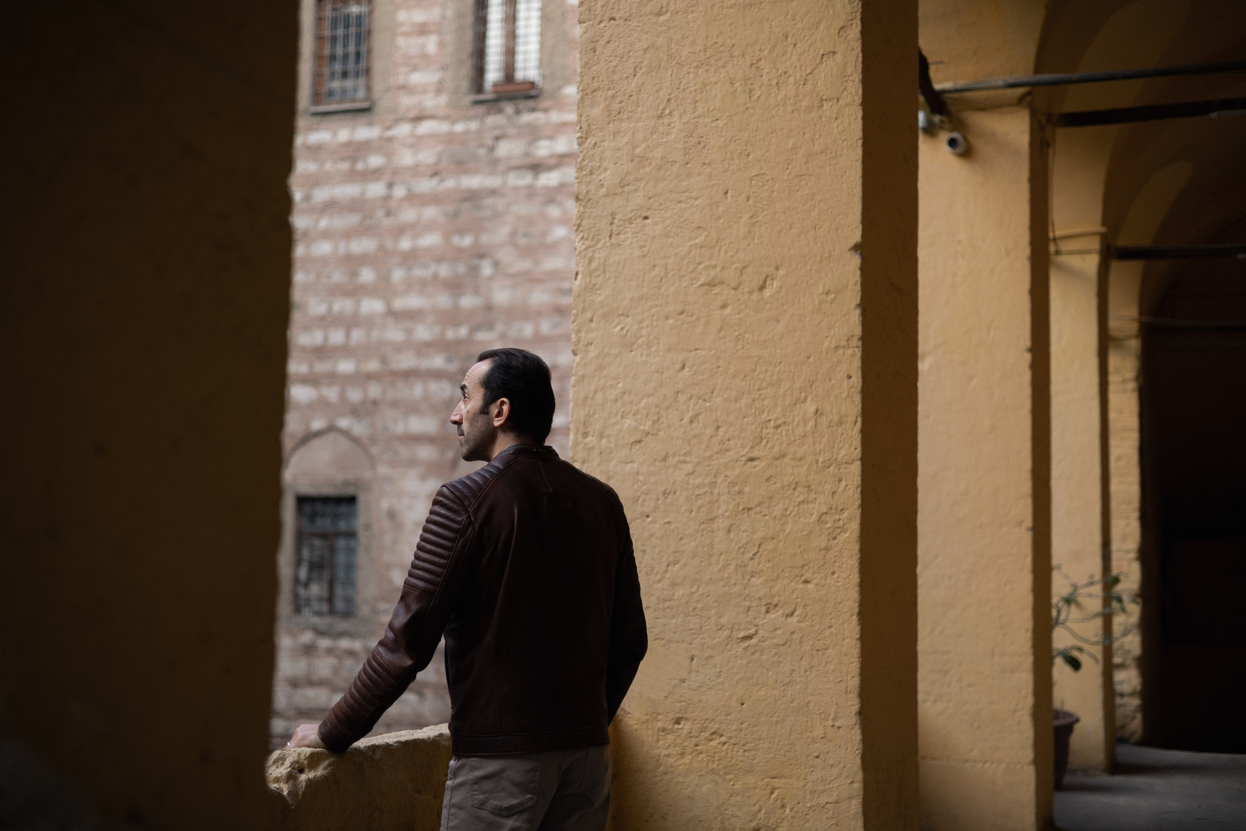 Мужской портрет в Стамбуле, мужчина опирается на каменный парапет старинной аркады и смотрит в сторону.