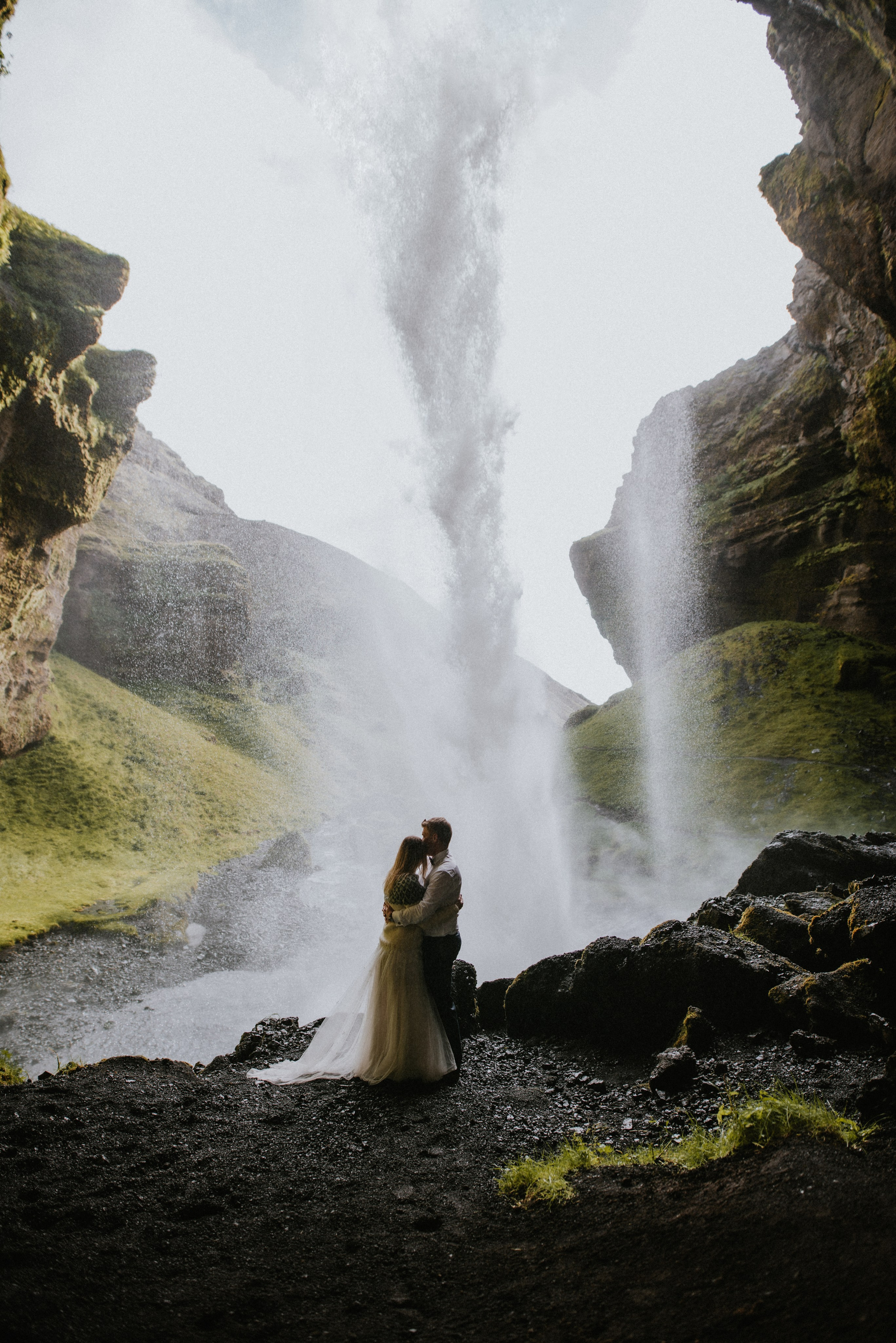 Romantic wedding couple embracing against the backdrop of a stunning Icelandic waterfall