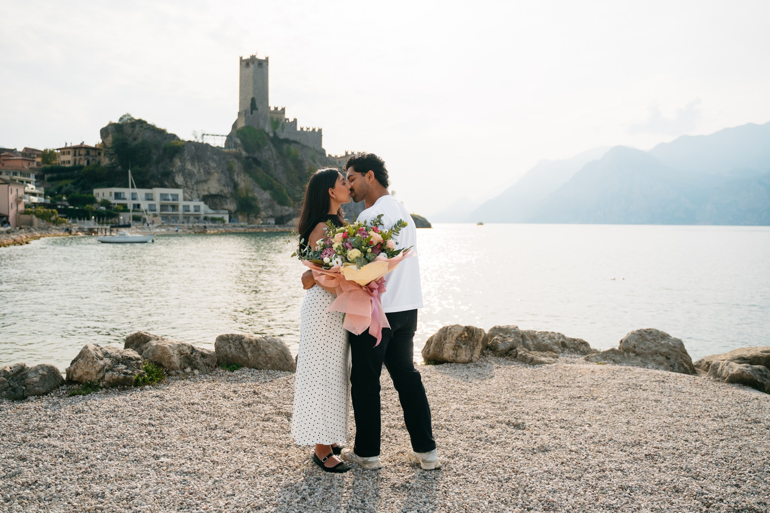 A couple getting engaged with Malcesine Castle and Lake Garda in the background.