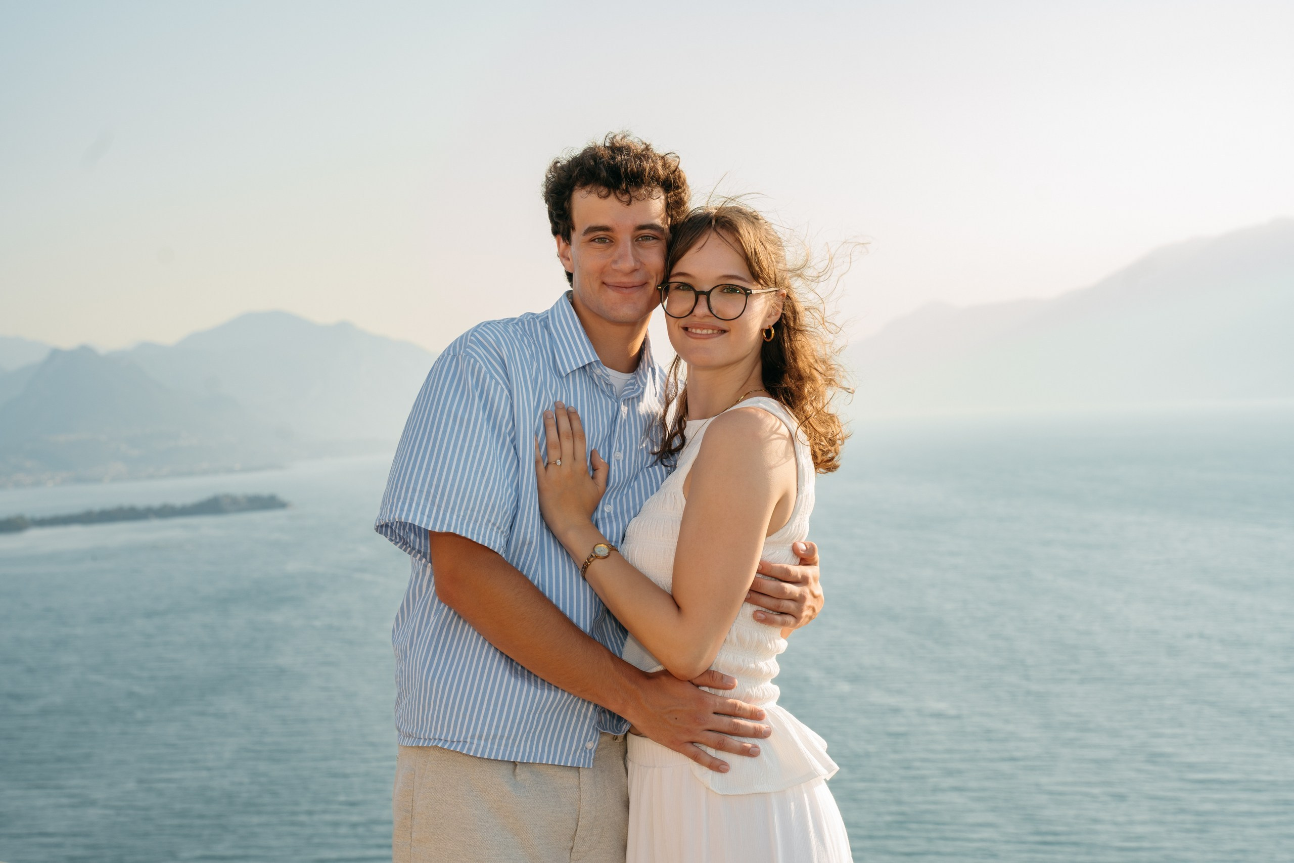 A couple standing together above Lake Garda after an early morning marriage proposal.