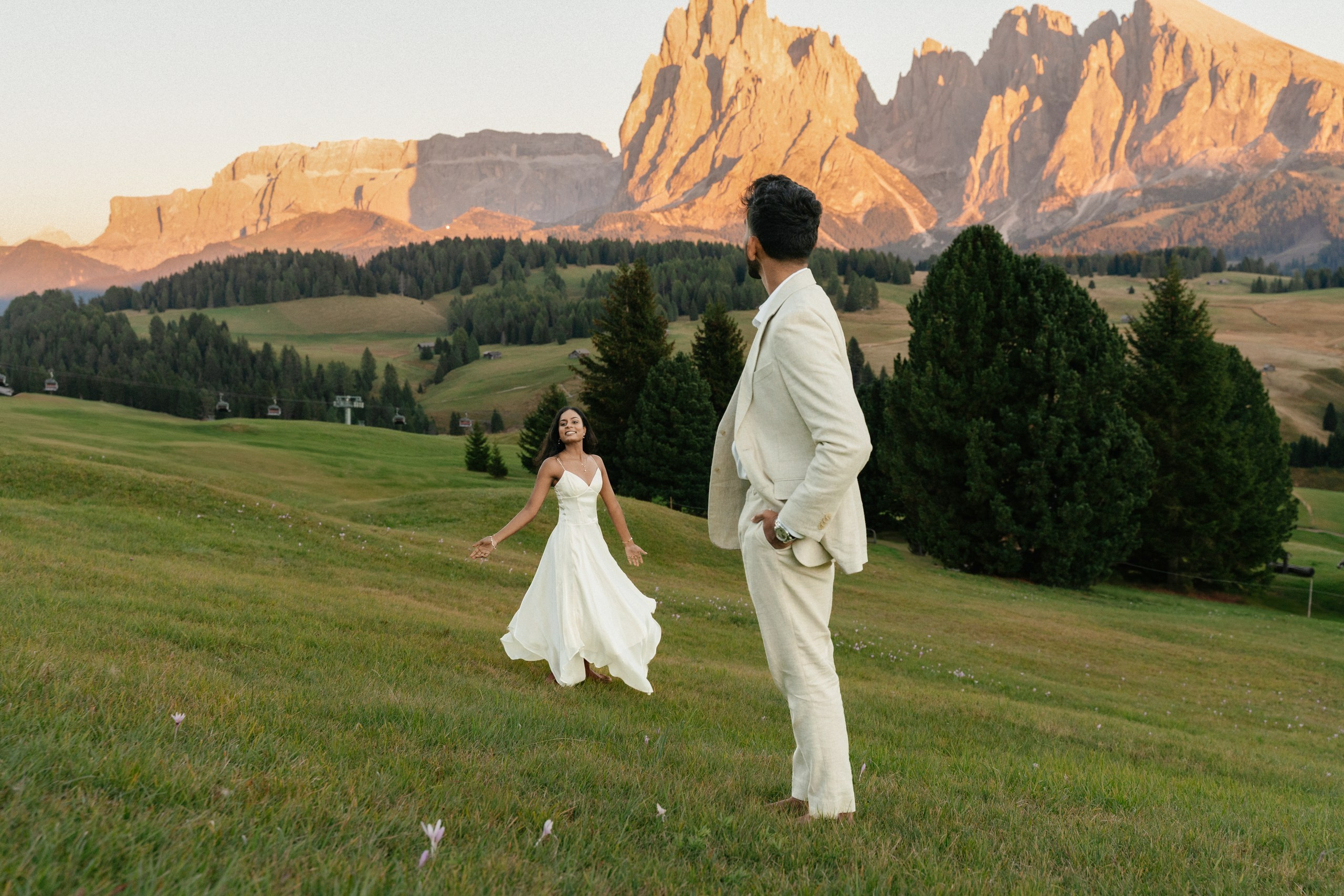 A couple dancing against the mountain panorama of Alpe di Siusi.