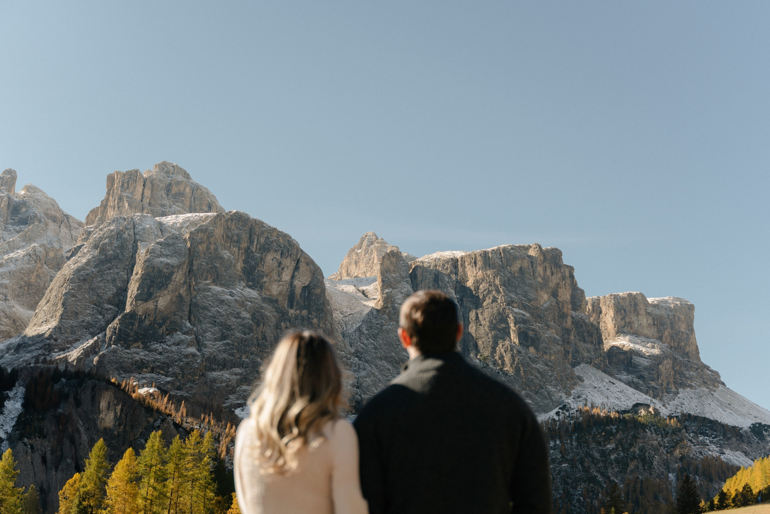 Couple looking out over the alpine scenery of Alta Badia in the Italian Dolomites.