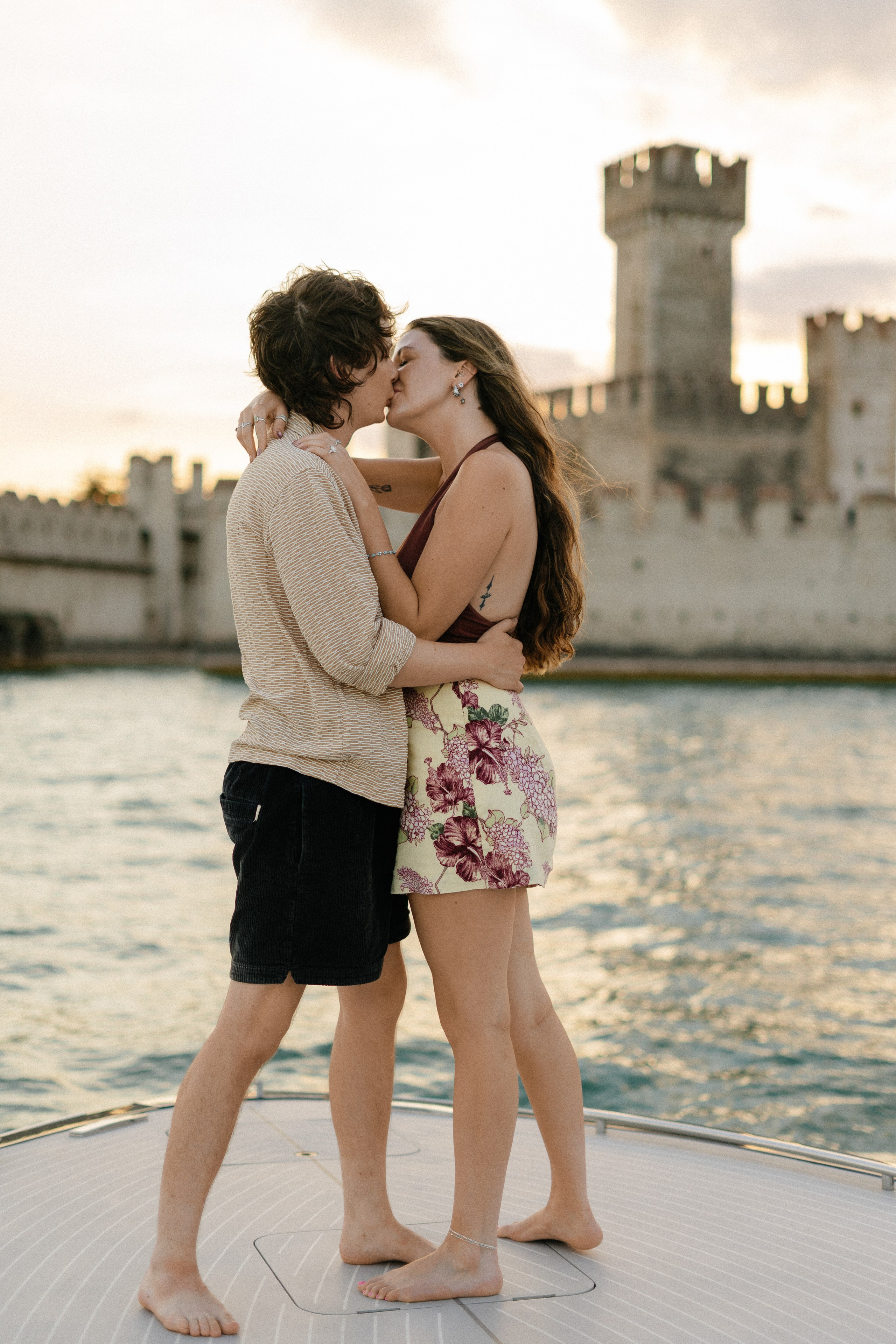 Couple embracing and kissing after their marriage proposal on a private boat in Sirmione, Italy.