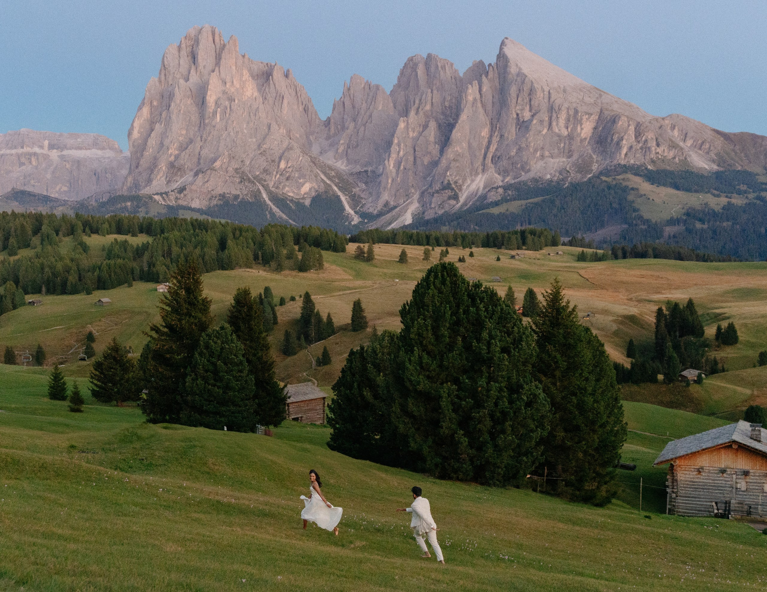 A couple running through the mountain landscape after their proposal on Alpe di Siusi.