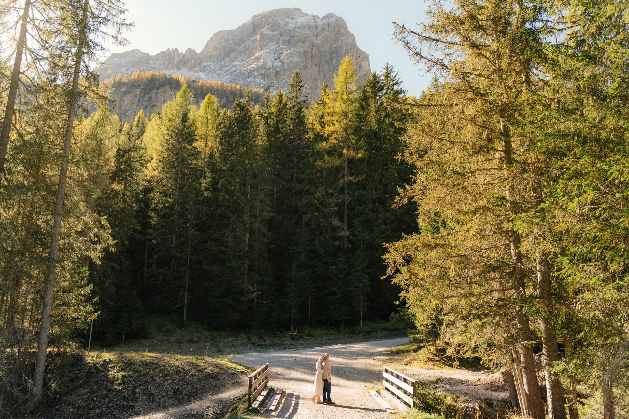 Couple embracing on a mountain trail surrounded by autumn colours and Dolomite peaks.