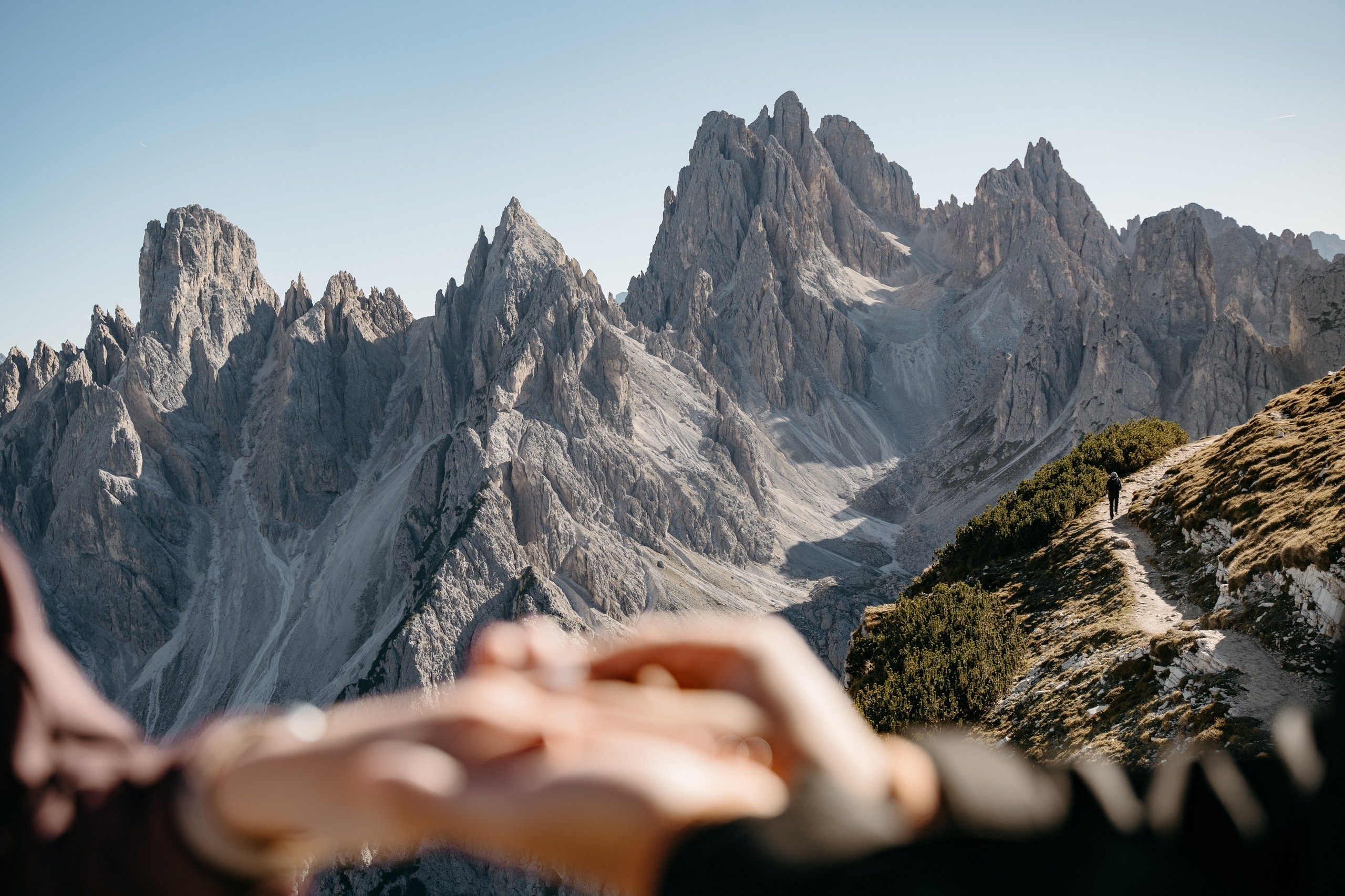 Newly engaged Asian partners holding hands with the Cadini di Misurina mountains in the background.