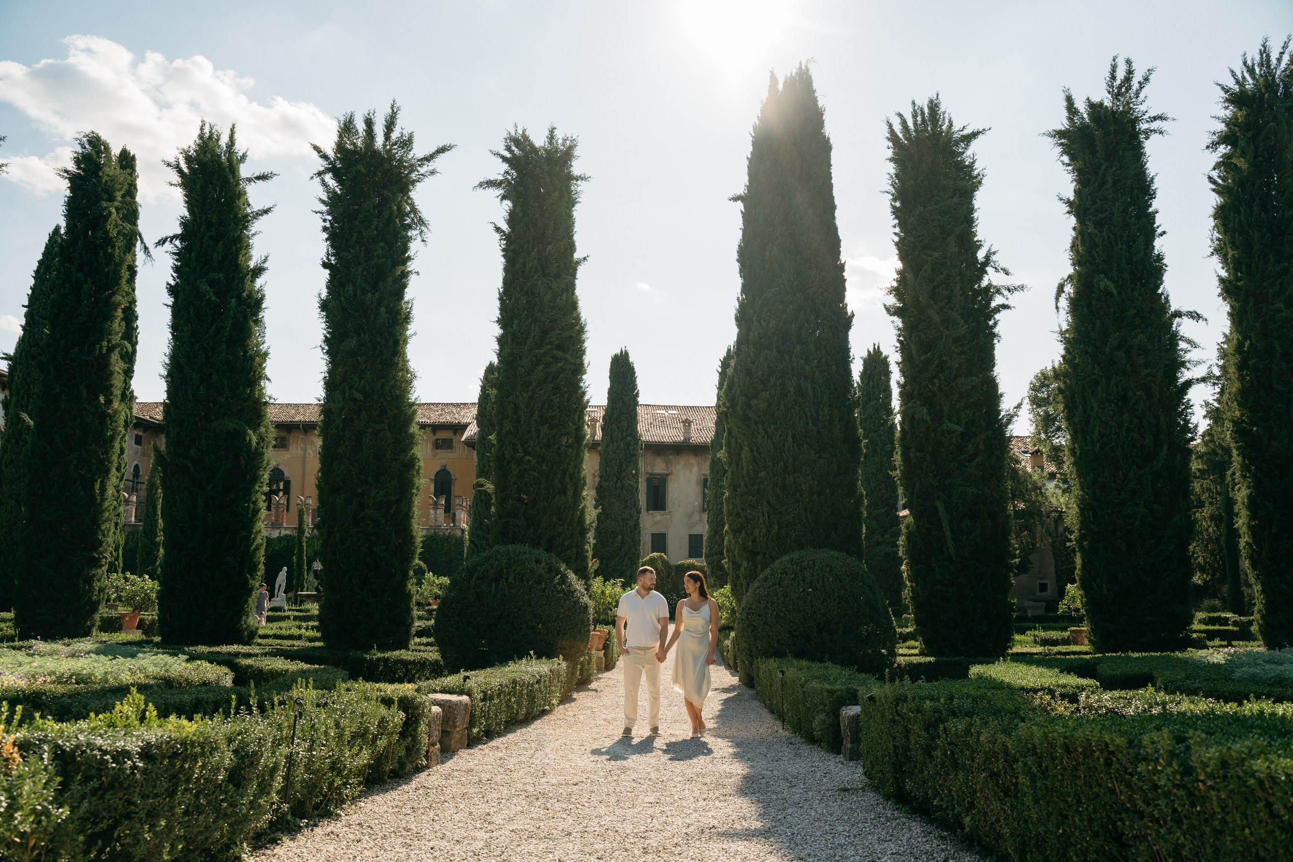 A couple standing together along a garden path at Giardino Giusti during their engagement session.