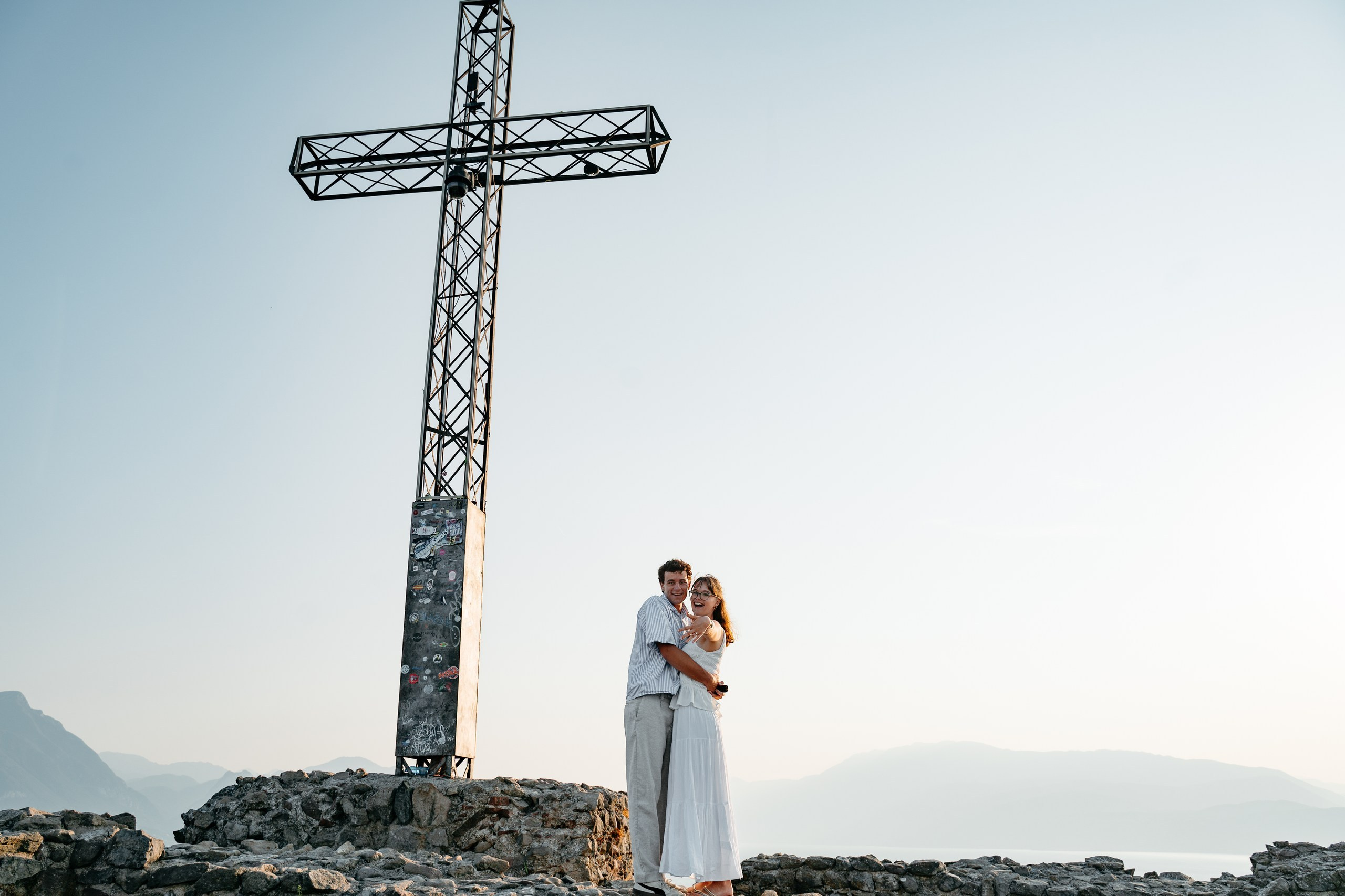 A young couple embracing after their proposal with panoramic views of Lake Garda.