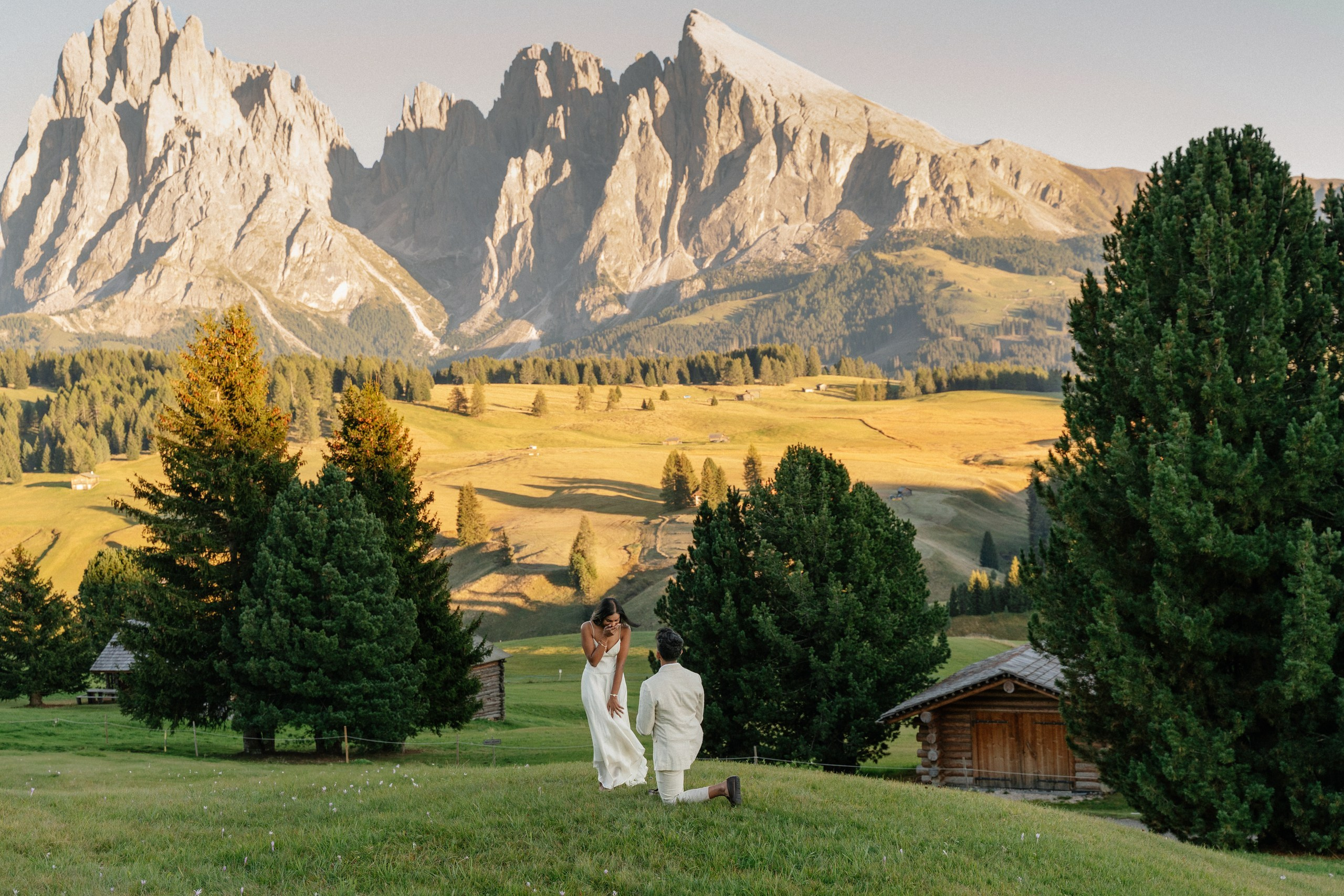 A couple getting engaged near Alpe Lodge on Alpe di Siusi, with the Dolomites in the background.
