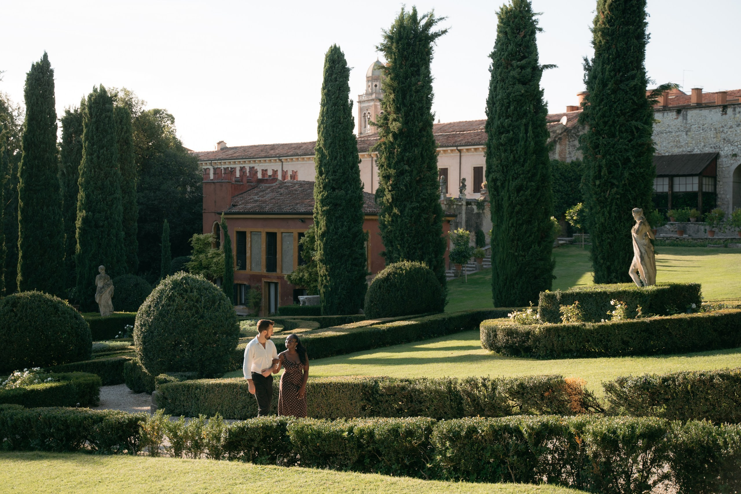 An interracial couple walking together through Giardino Giusti during their engagement photoshoot.