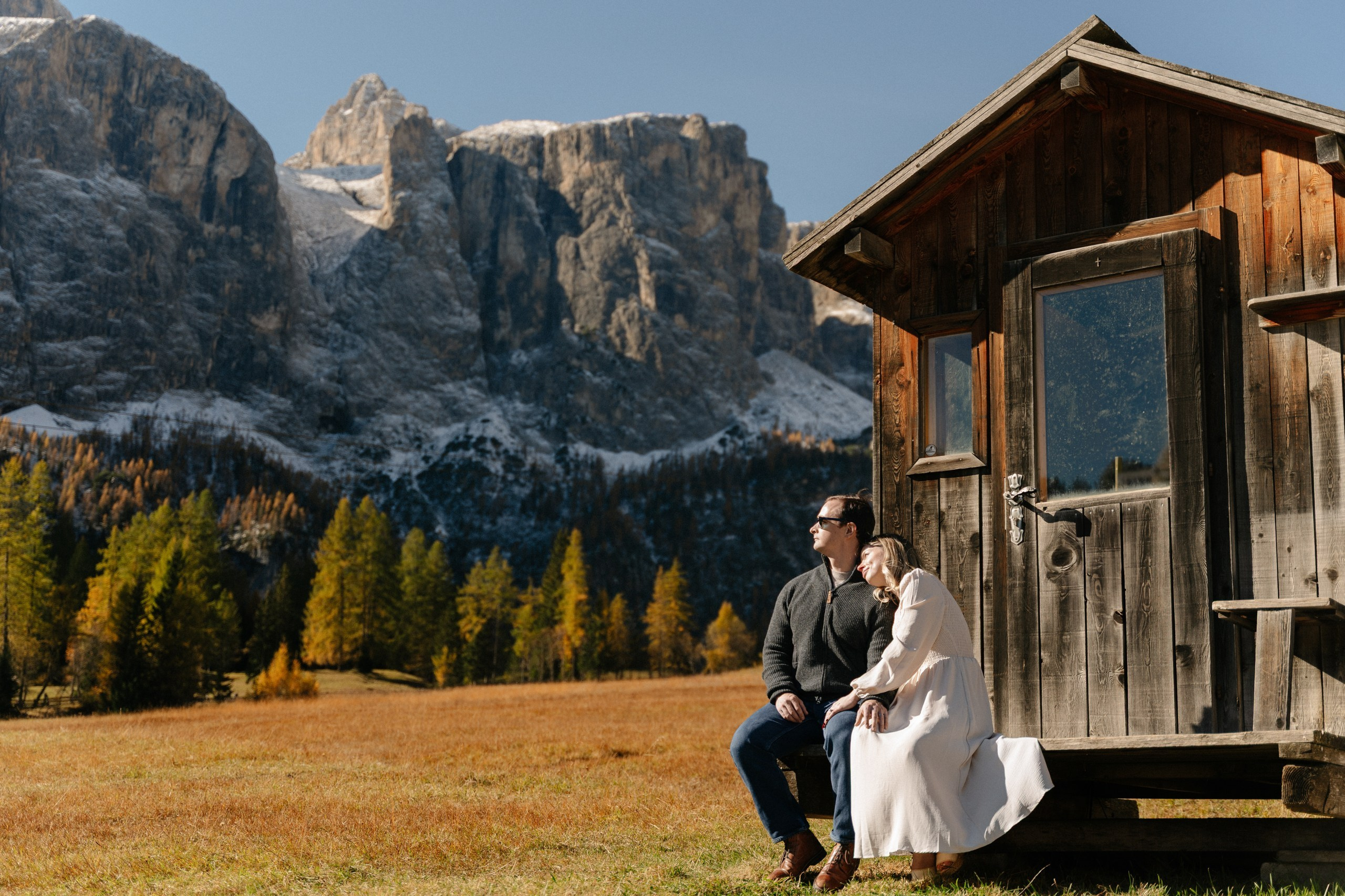 Couple standing cheek to cheek with the mountains of Alta Badia in the background.