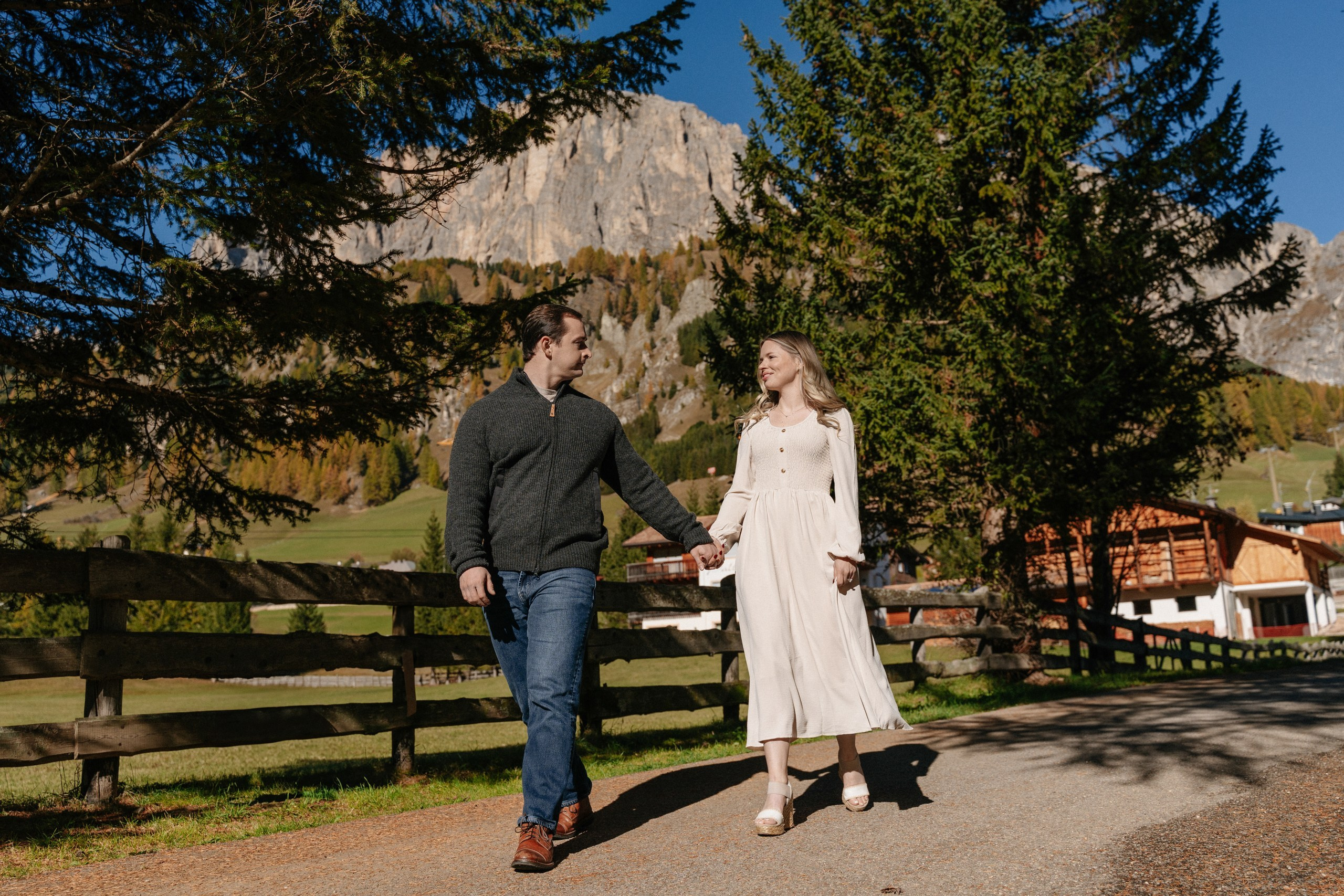 Couple walking hand in hand along a mountain path during a love story photoshoot in Alta Badia, Colfosco