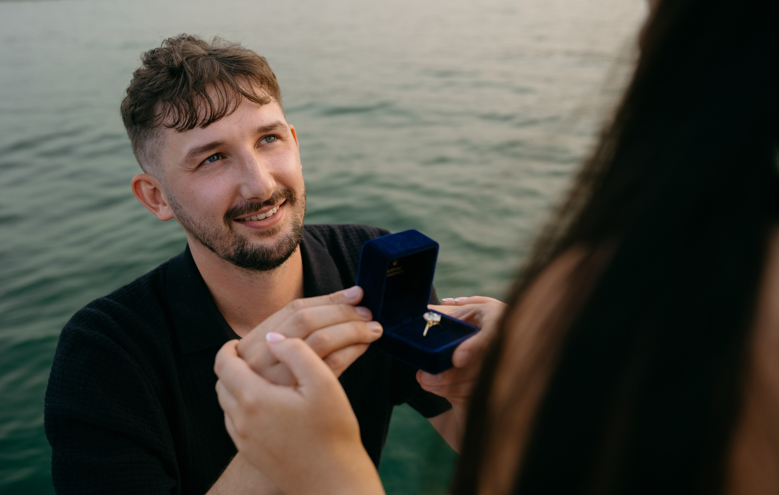 Close-up of an engagement ring with Lake Garda and the Sirmione shoreline in the background.