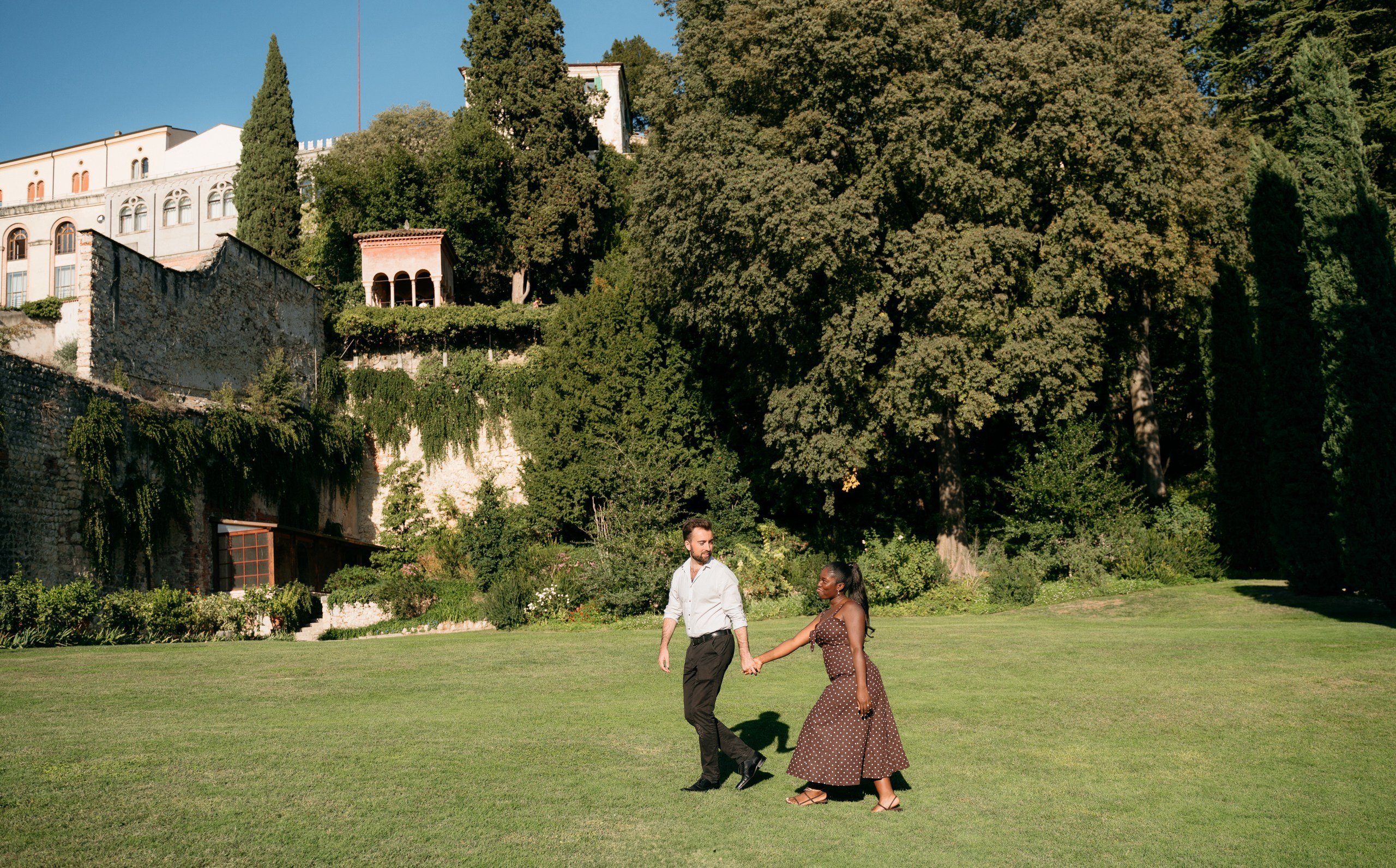 A couple holding hands among the greenery after getting engaged at Giardino Giusti.