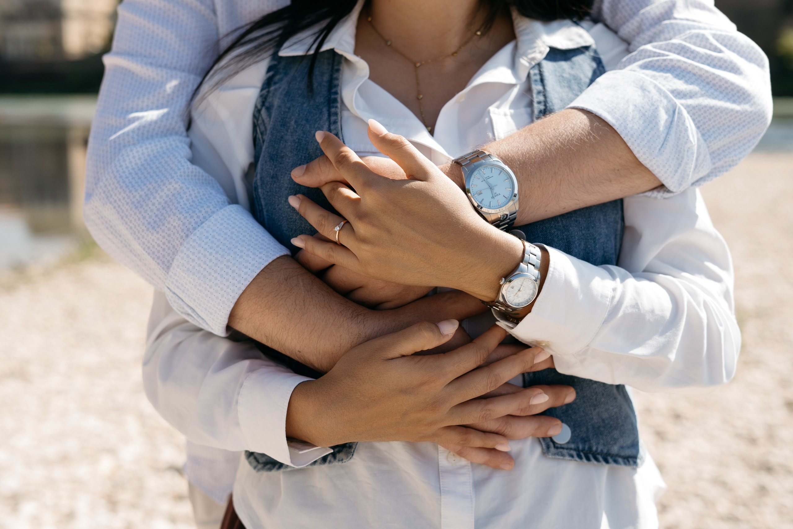 Newly engaged couple holding hands by the Adige River with Castelvecchio Bridge in the background.