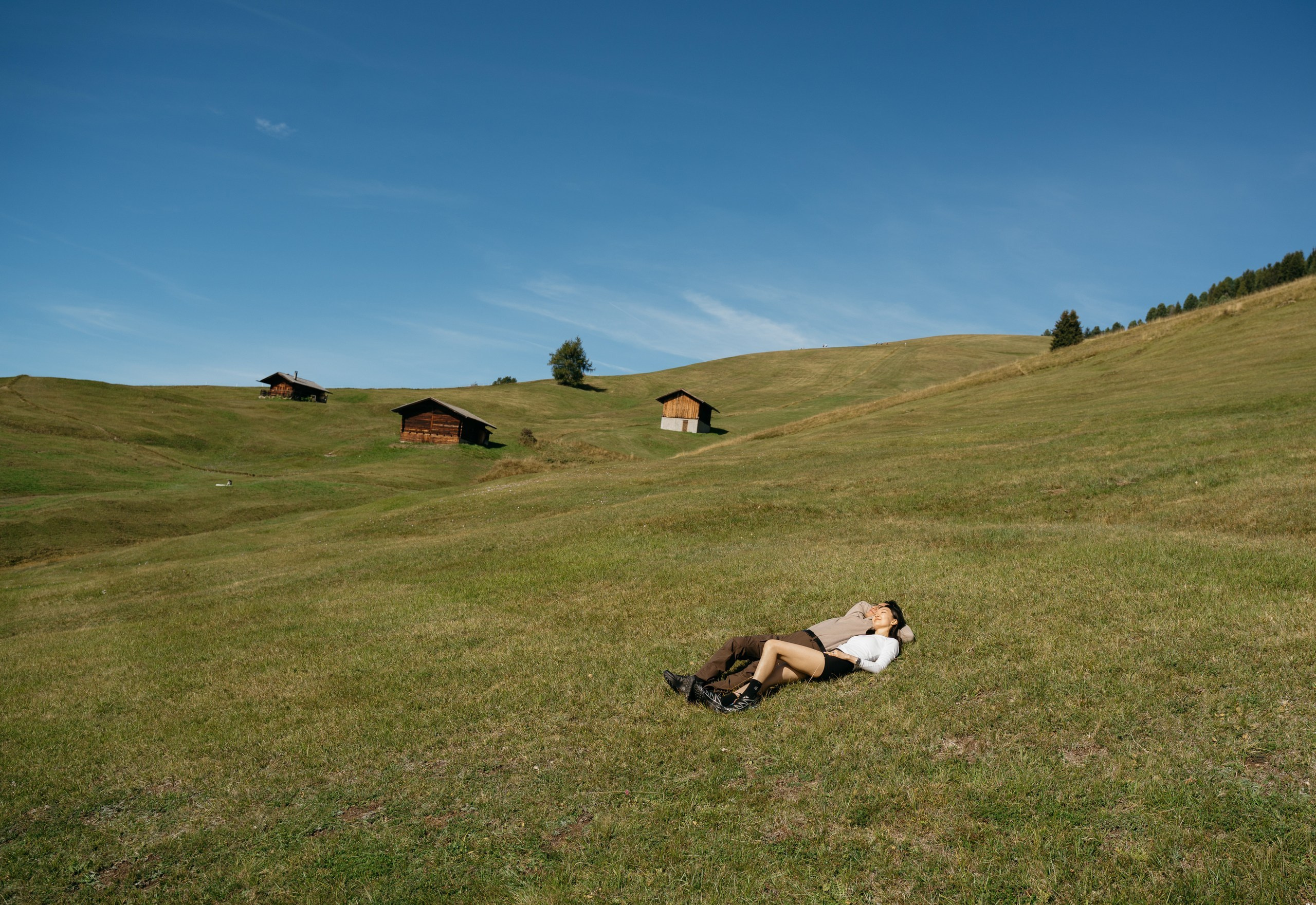 A distant view of the newly engaged couple beneath the Dolomite peaks on Alpe di Siusi.