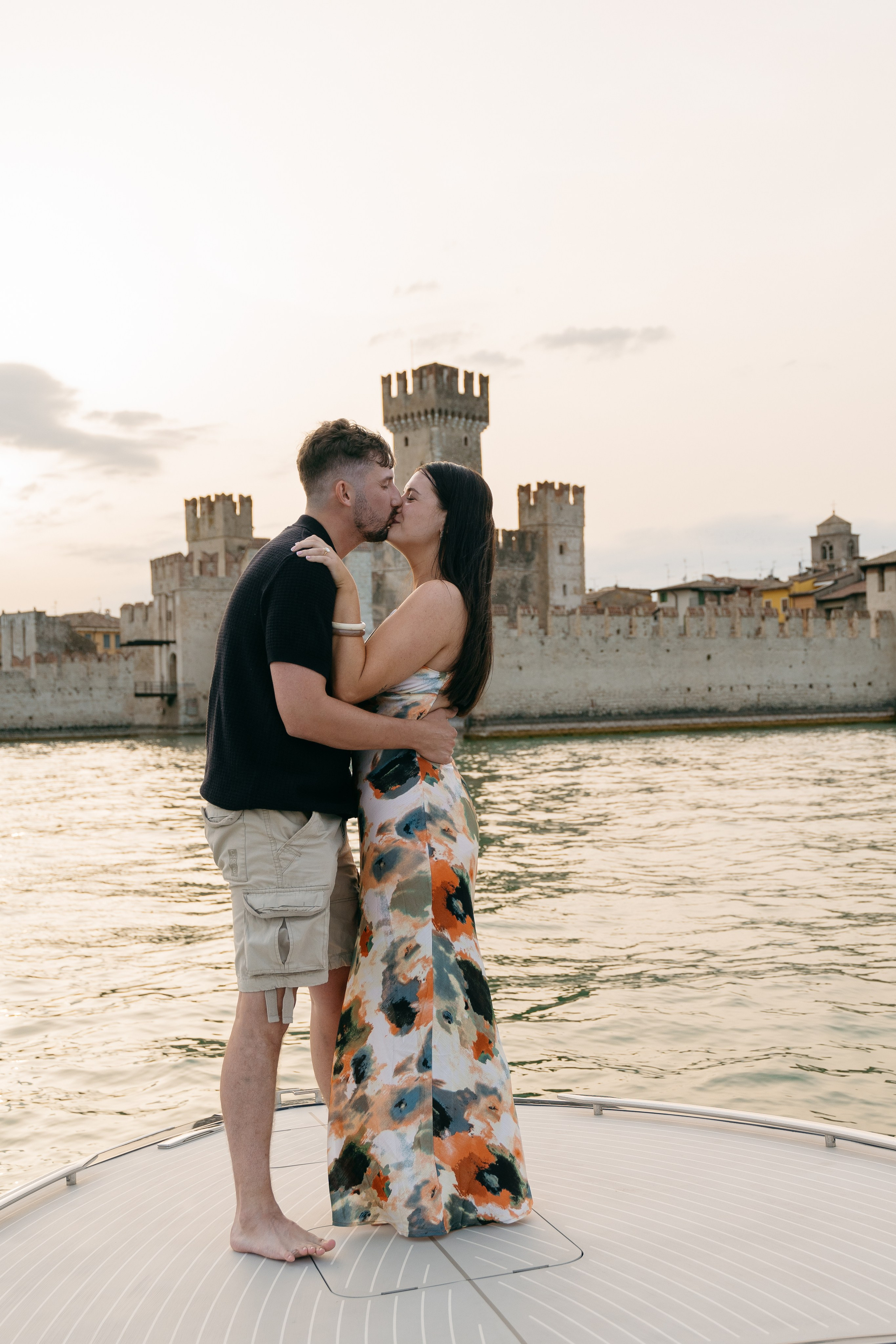 Newly engaged couple sharing a romantic moment on the bow of a luxury boat in Italy.