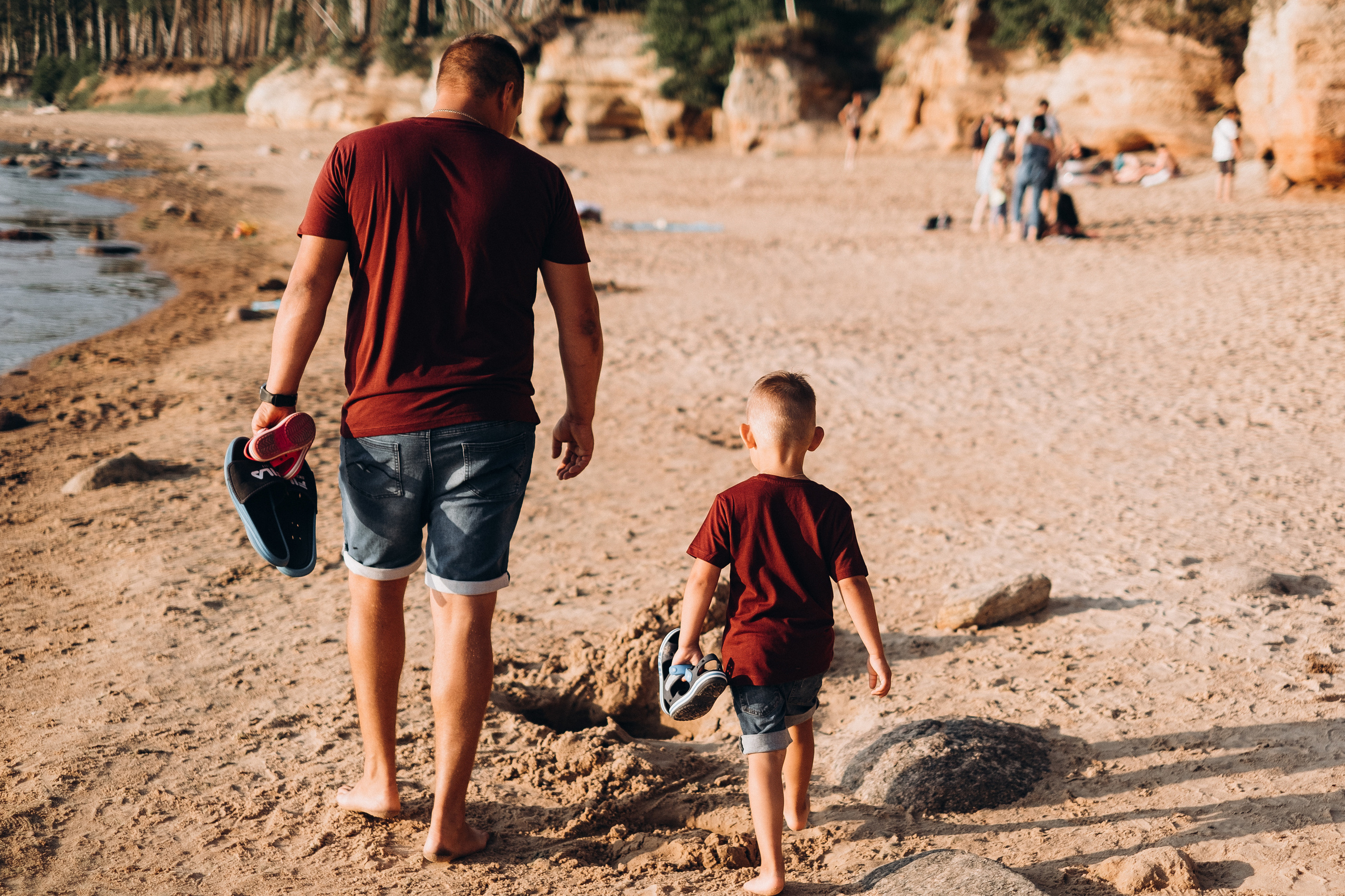 Tēvs un dēls iet gar jūru pa pludmali blakus Veczemju klintīm.