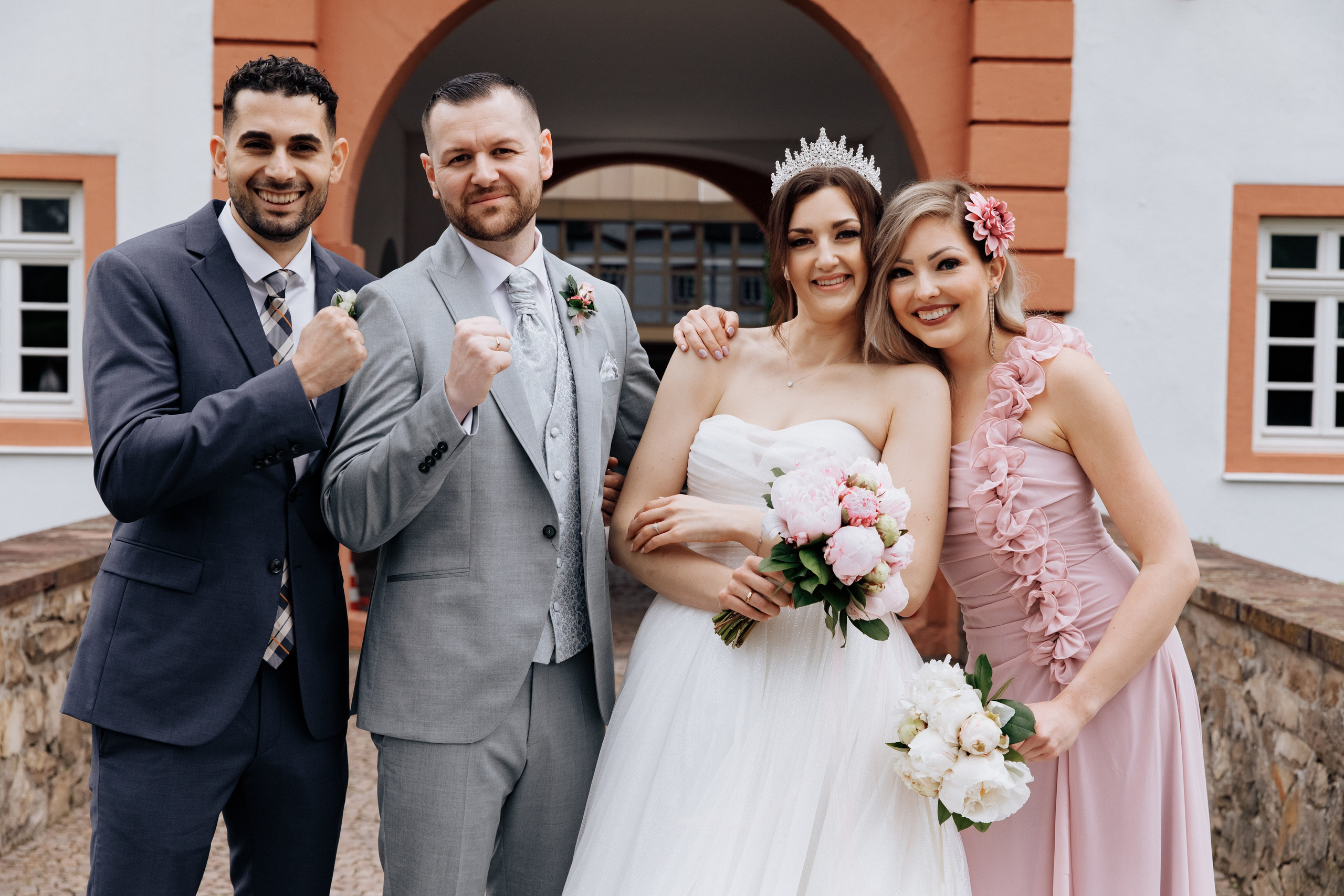 Der Bräutigam, die Braut und ihre Trauzeugen lachen und lächeln zusammen.