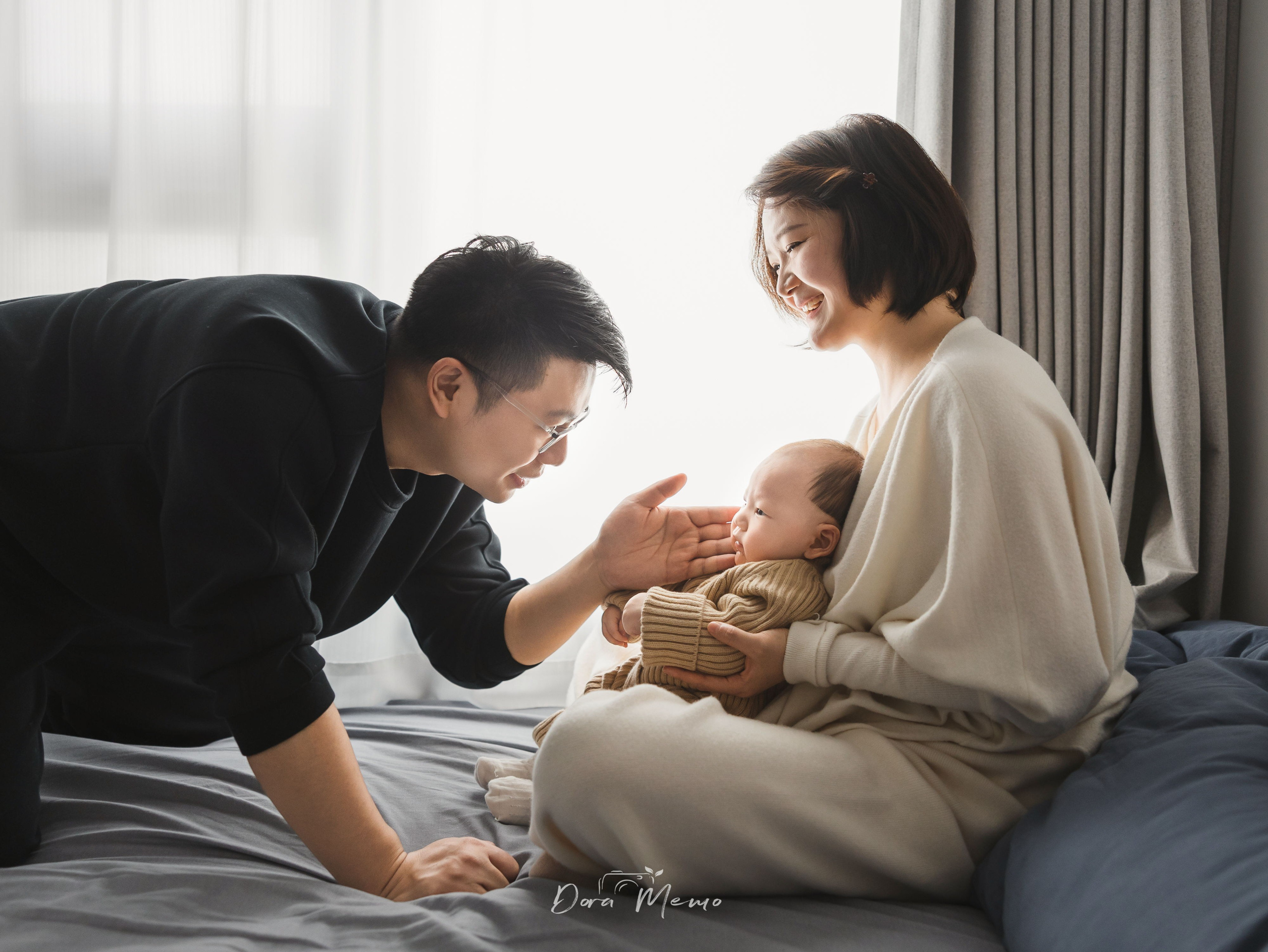 Father gently touching baby face while mother smiling, lifestyle family session at home