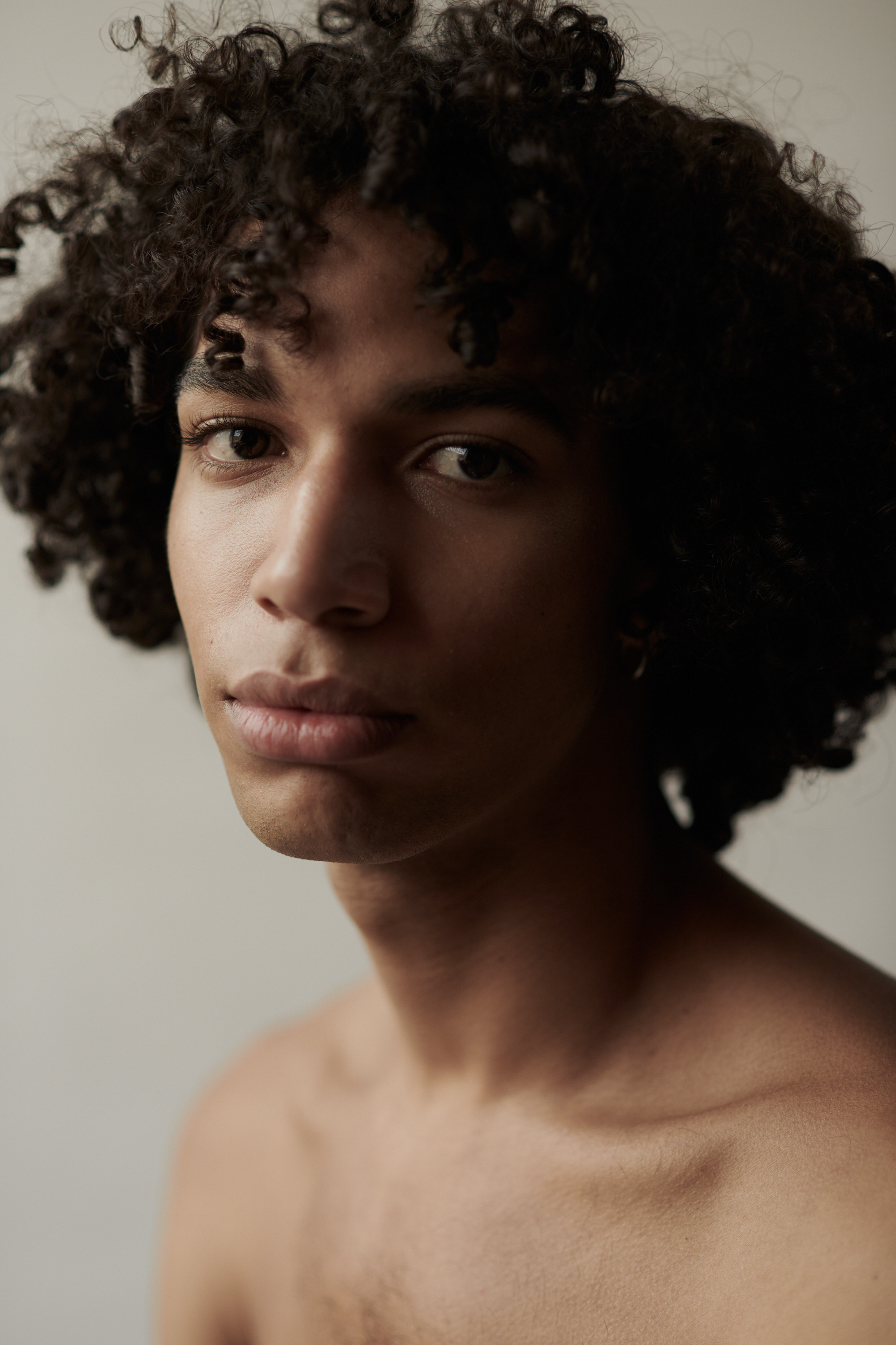 Studioportret van een jonge man met krullen. Fotograaf Amsterdam - Victoria Ushkanova