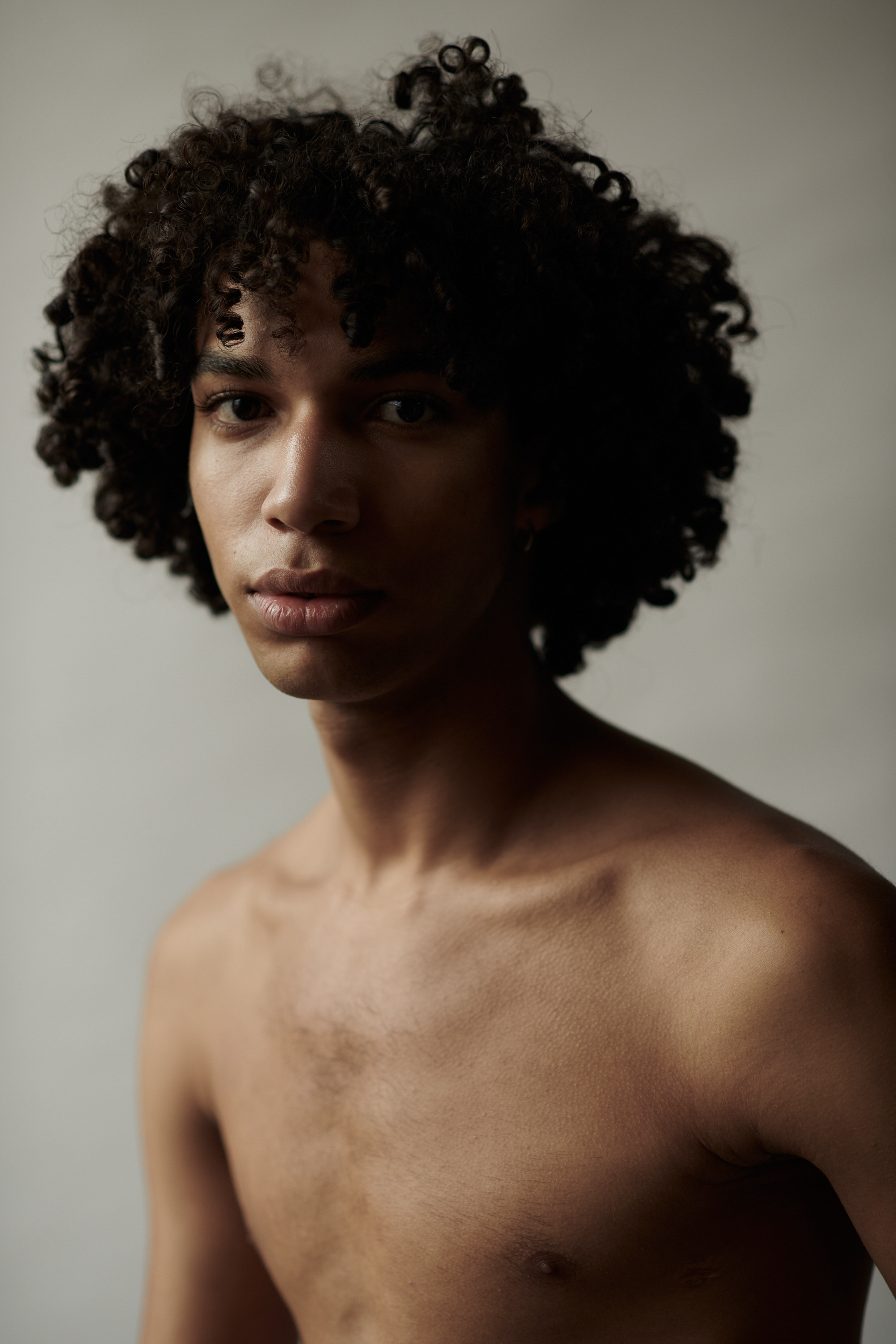 Studioportret van een jonge man met krullen. Fotograaf Amsterdam - Victoria Ushkanova