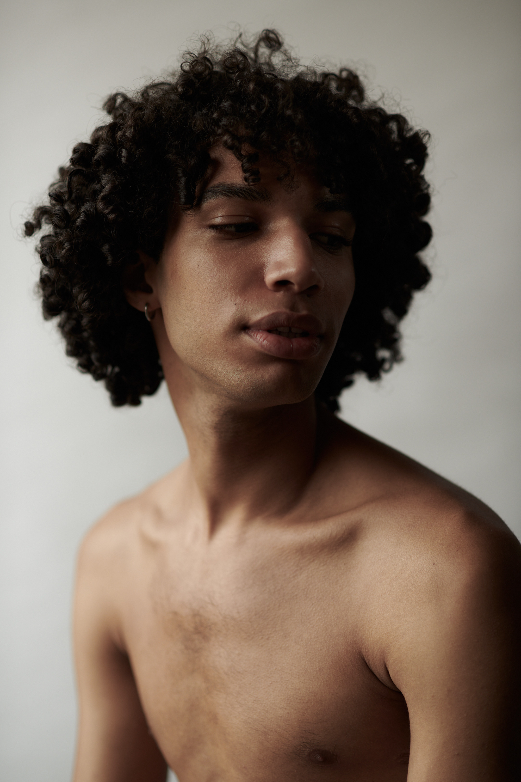 Studioportret van een jonge man met krullen. Fotograaf Amsterdam - Victoria Ushkanova