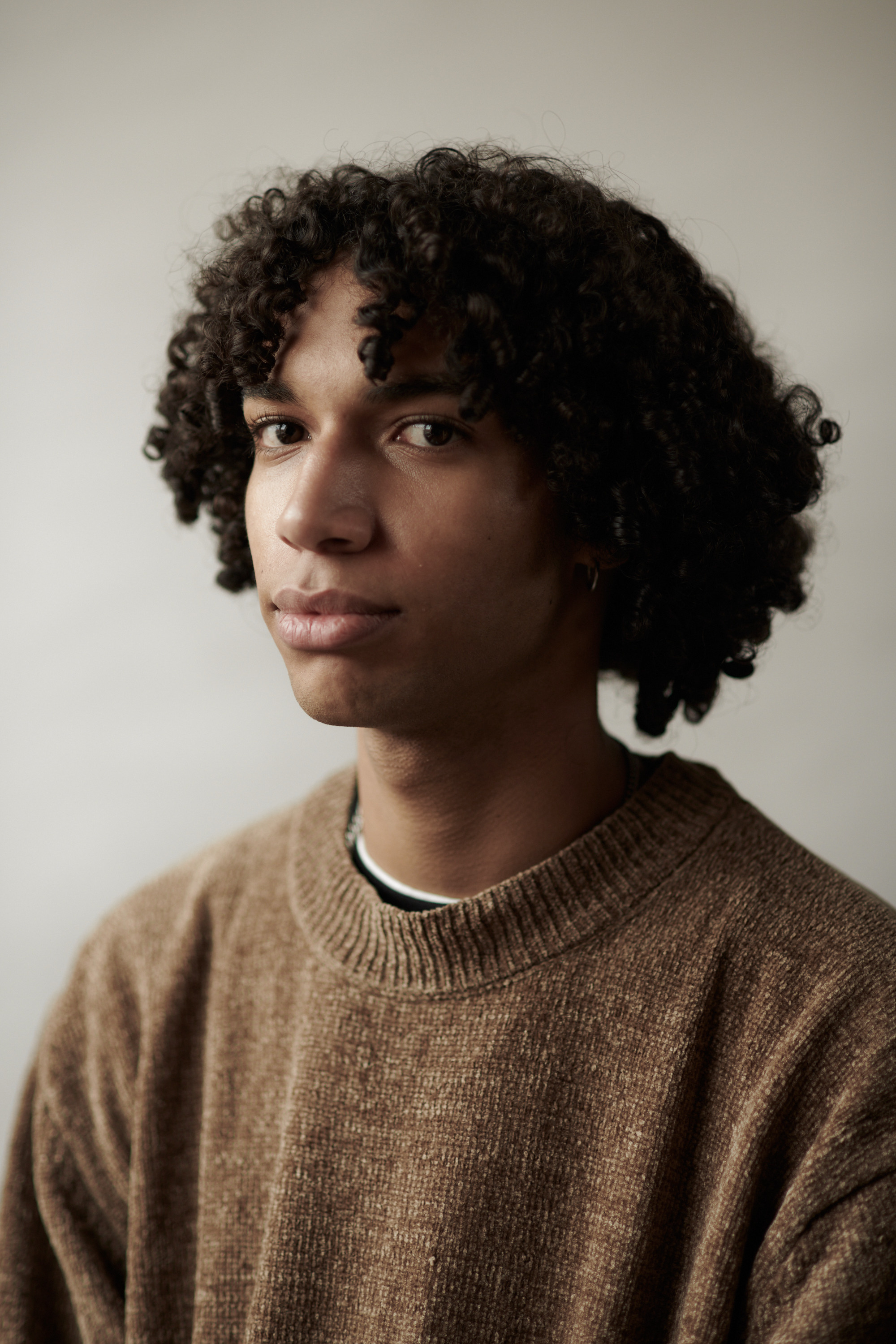 Studioportret van een jonge man met krullen. Fotograaf Amsterdam - Victoria Ushkanova