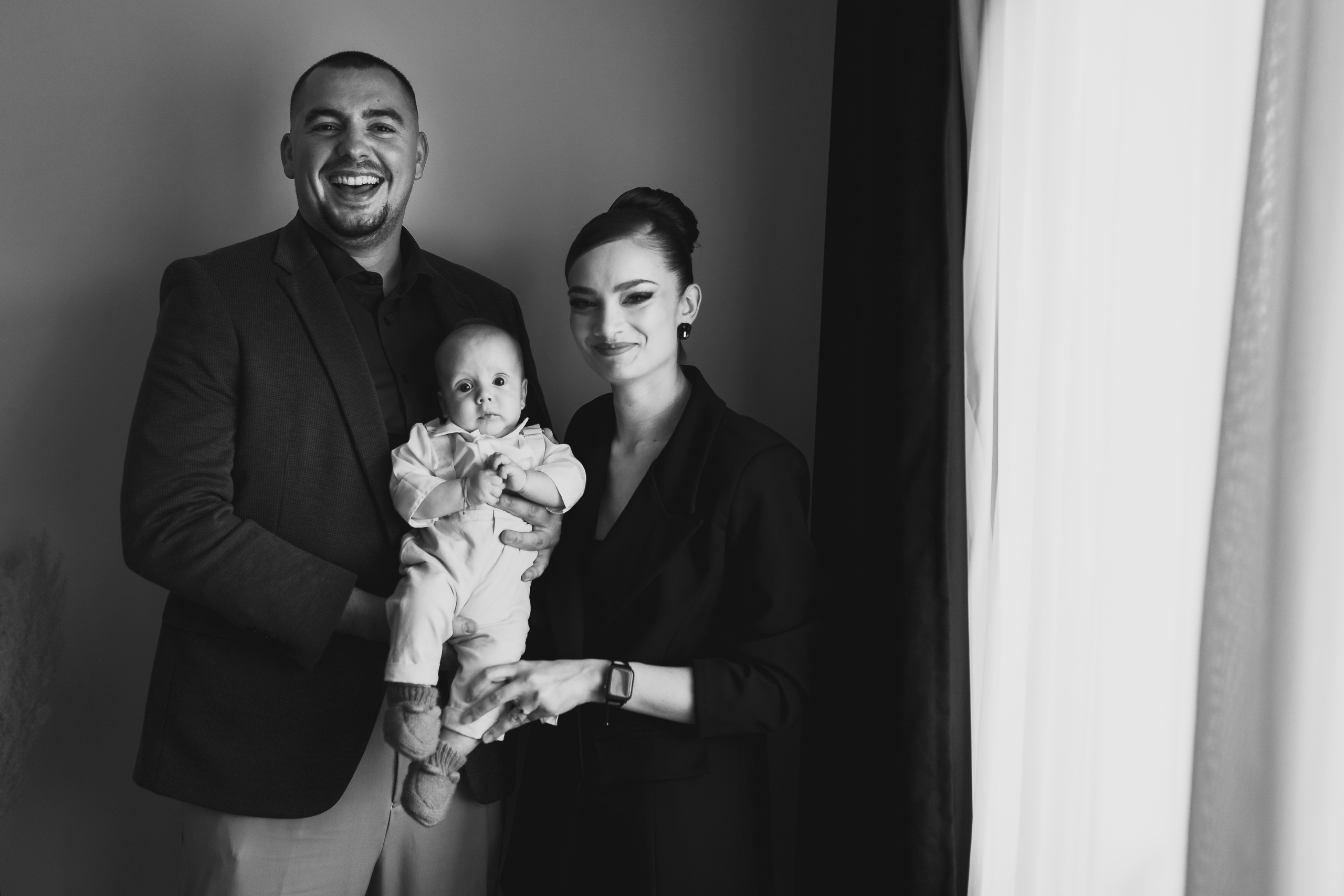 Instantaneu plin de tandrețe dintre părinți și bebeluș în ziua botezului, realizat în Craiova. Fotografie profesională de botez, capturând emoțiile autentice ale familiei într-un decor luminos și cald