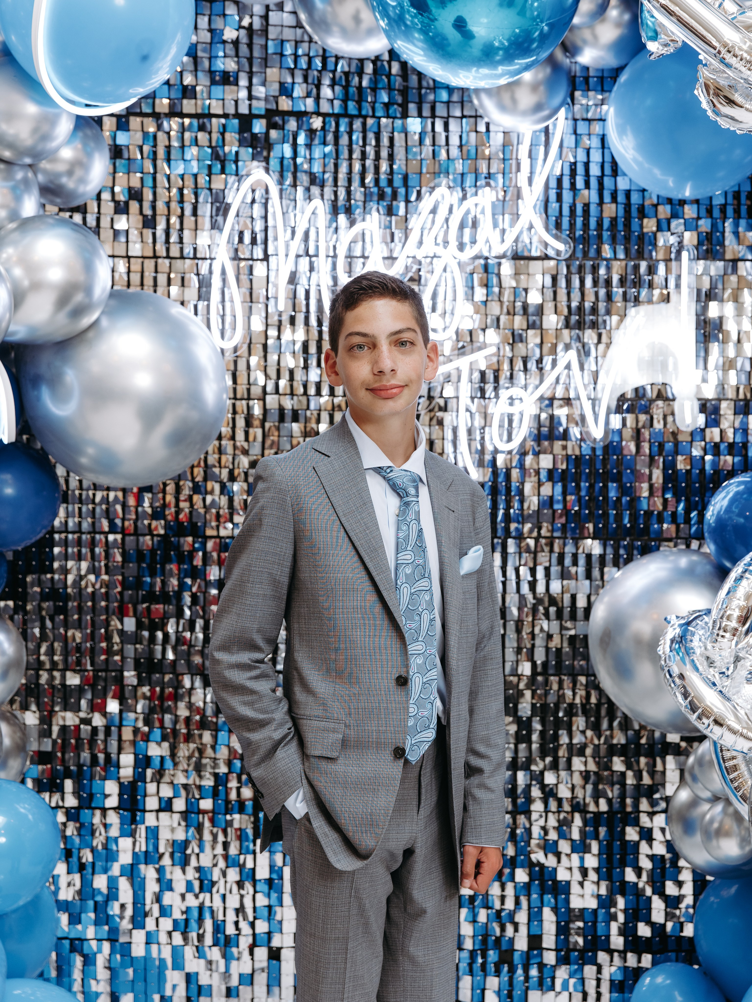 Bar Mitzvah boy portrait in Toronto with elegant formal look. Portrait of Bar Mitzvah boy in suit captured in natural light. Bar Mitzvah boy posing during celebration with confident expression. Candid portrait of Bar Mitzvah boy during event in GTA. Bar Mitzvah boy formal portrait with family event background.