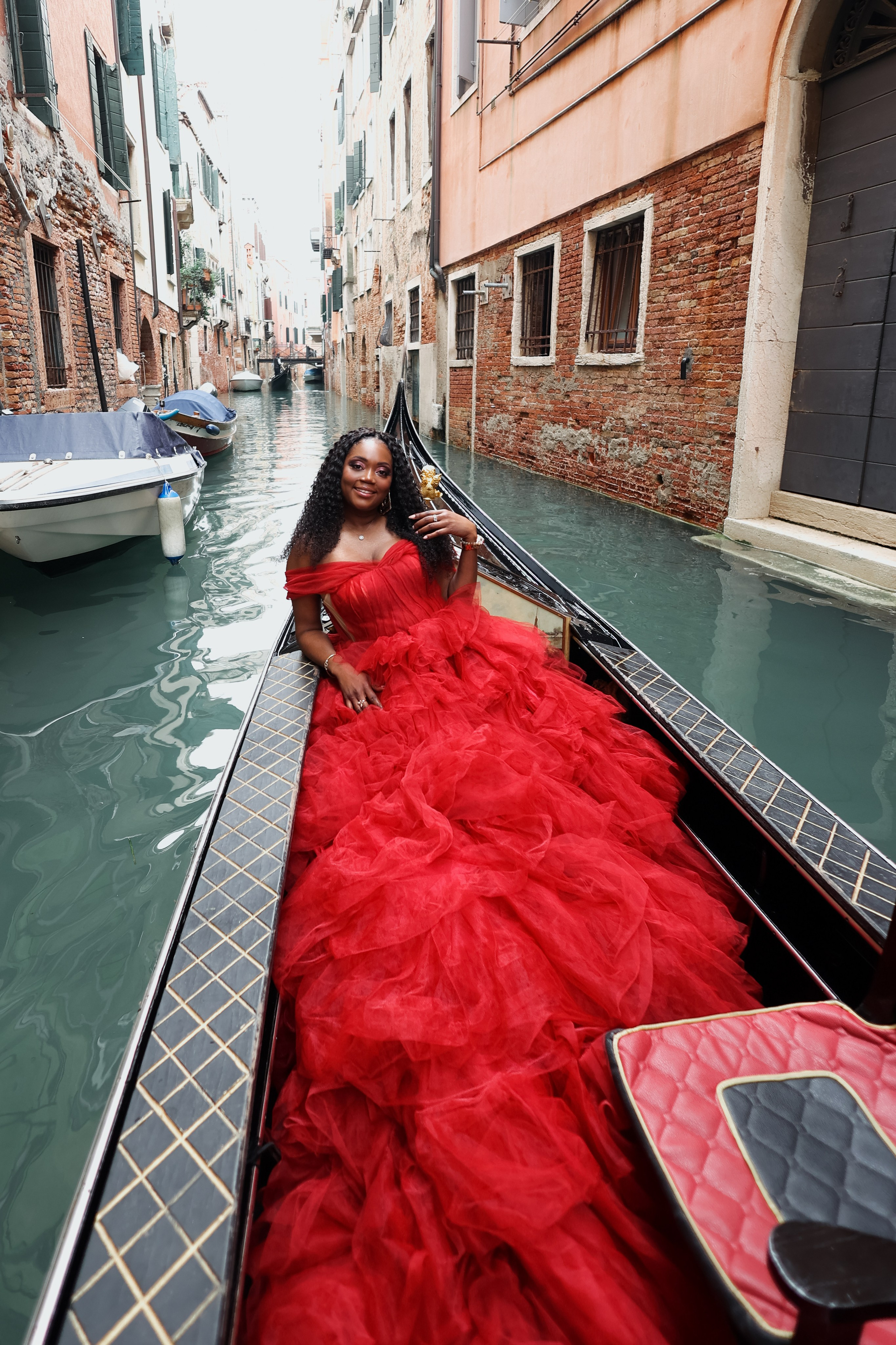 Girl in a red long dress on a gondola ride in Venice Italy