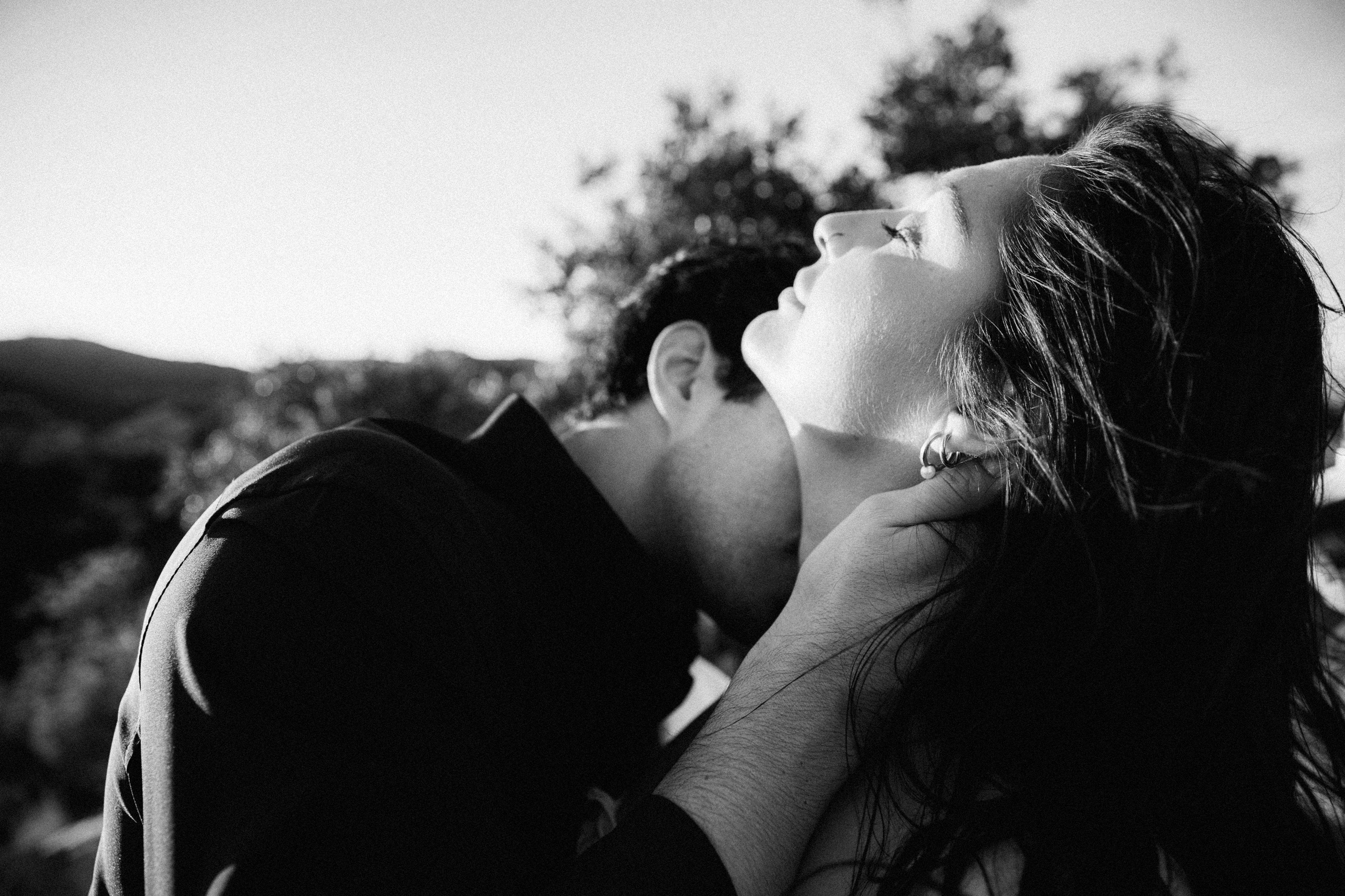 Close-up black and white portrait of bride and groom sharing an intimate kiss during a mountain elopement in Barcelona, Spain. The emotional moment captures the romance of a private destination wedding.