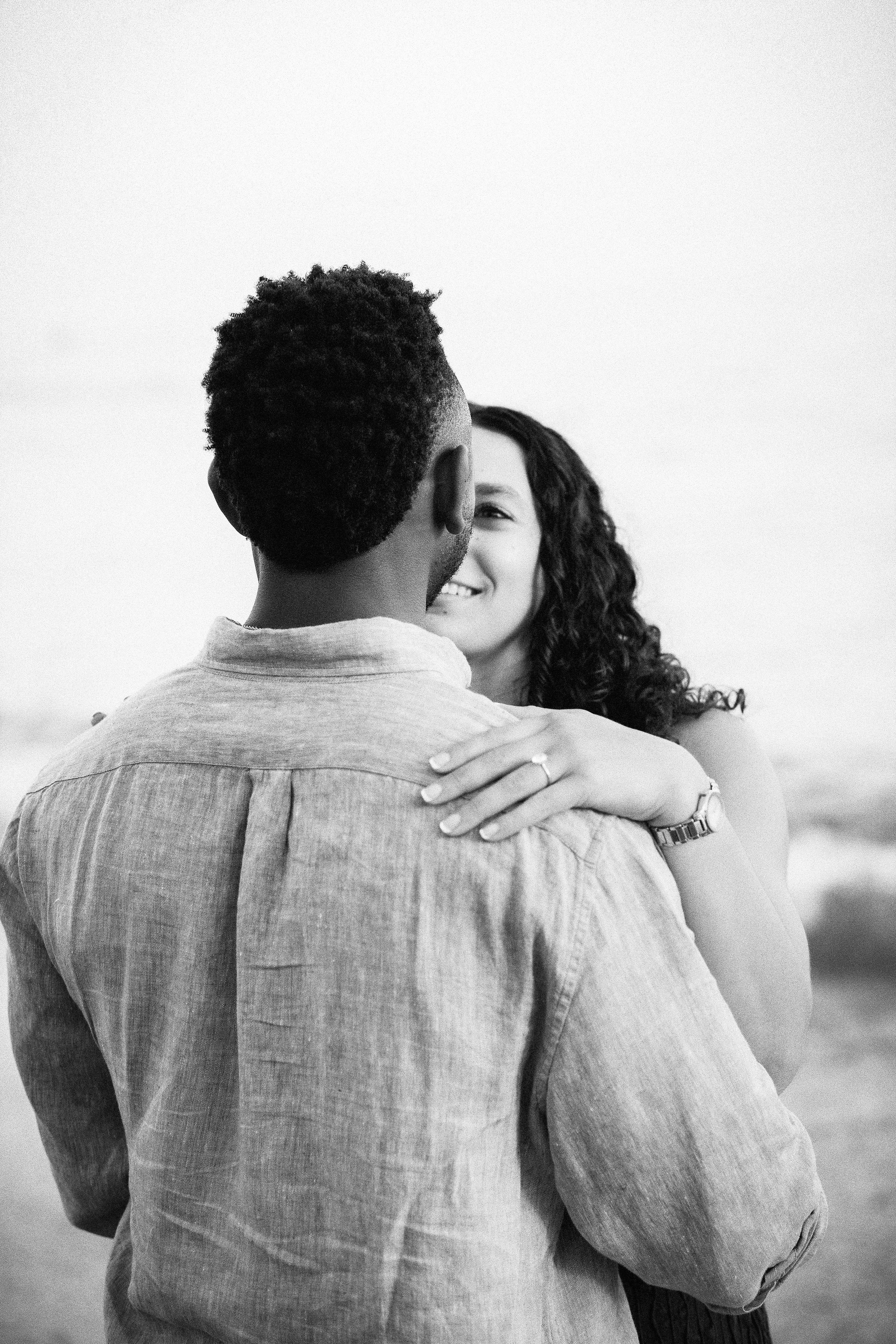 Newly engaged couple sharing a quiet embrace after their romantic proposal in Málaga. Destination engagement session by the sea highlighting natural connection and timeless black-and-white storytelling.