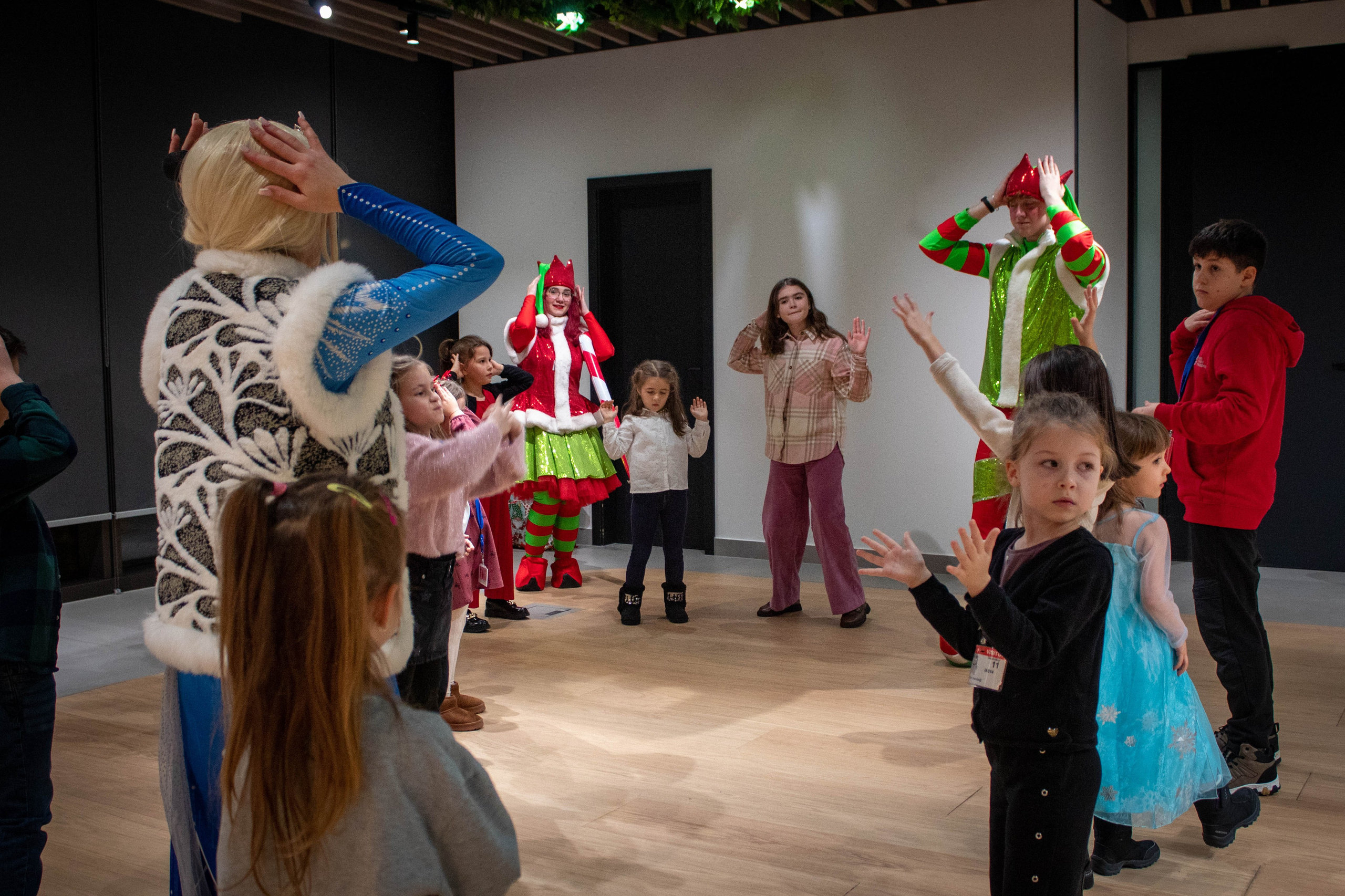 Performers dressed in costumes entertaining children on a stage in an indoor setting.