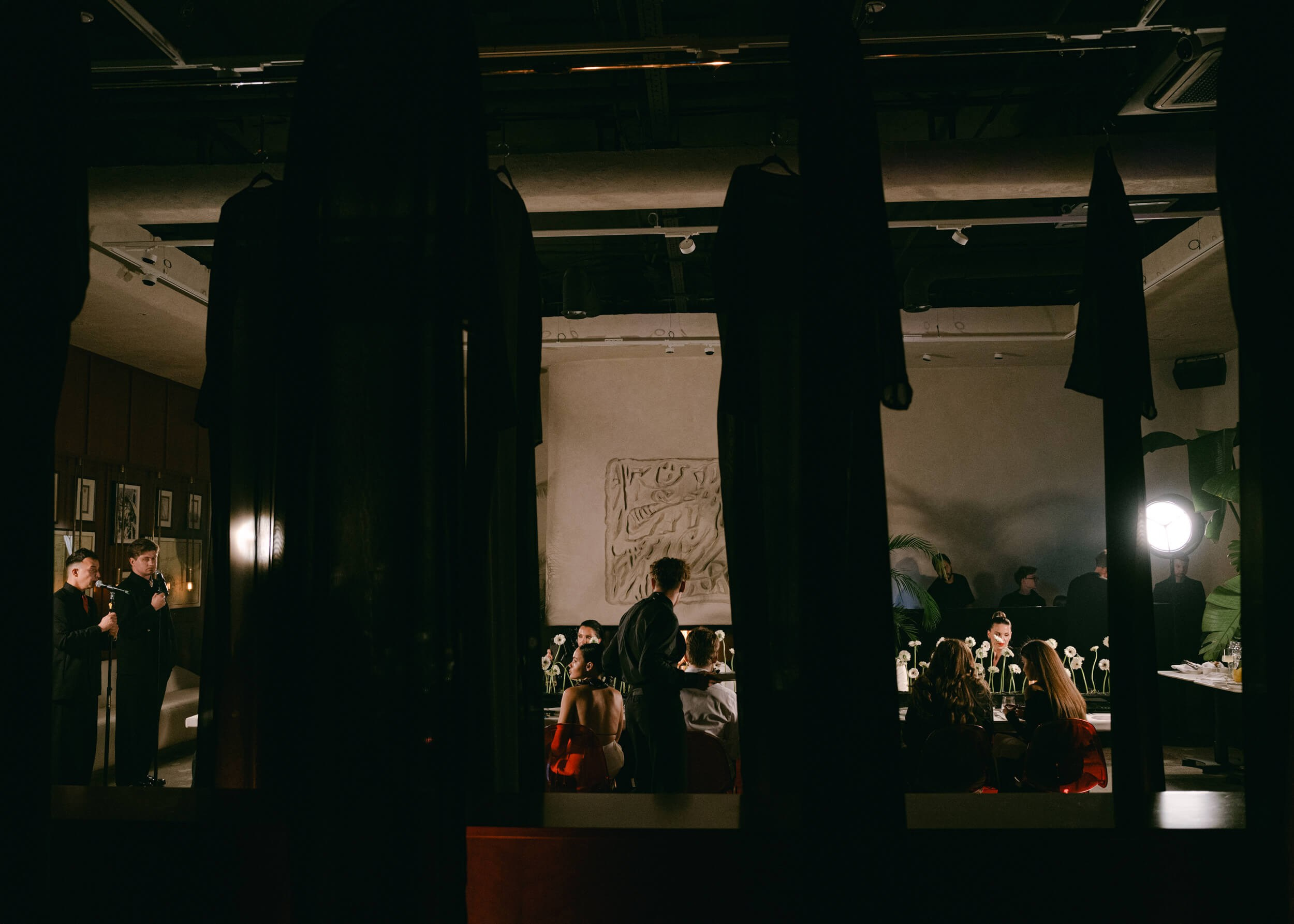 View through dark columns into a candlelit dinner room, atmospheric event photography in Milan