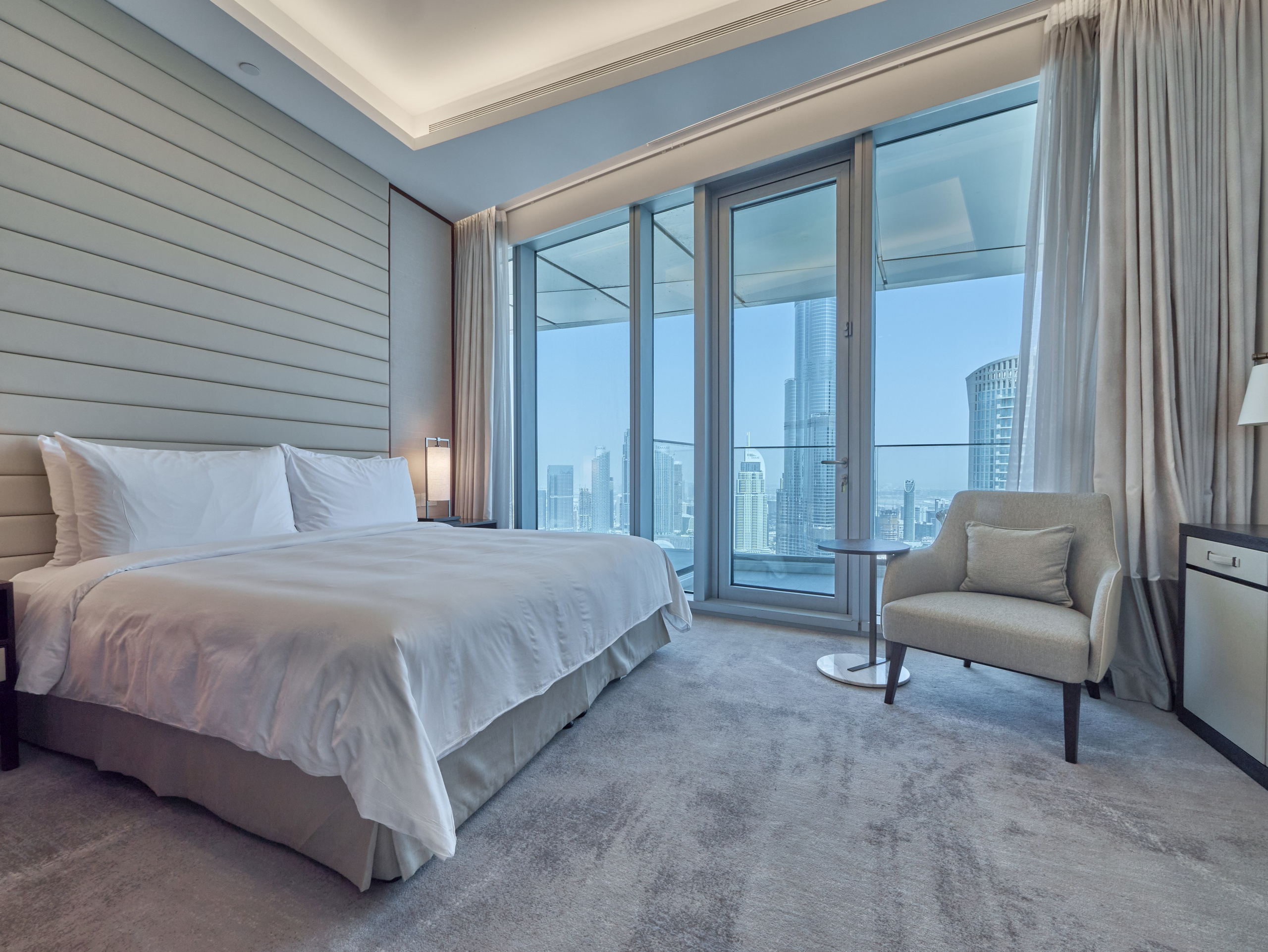 Spacious master bedroom with city skyline view, soft carpet and full-height windows — perfect for Airbnb and luxury real estate presentations.