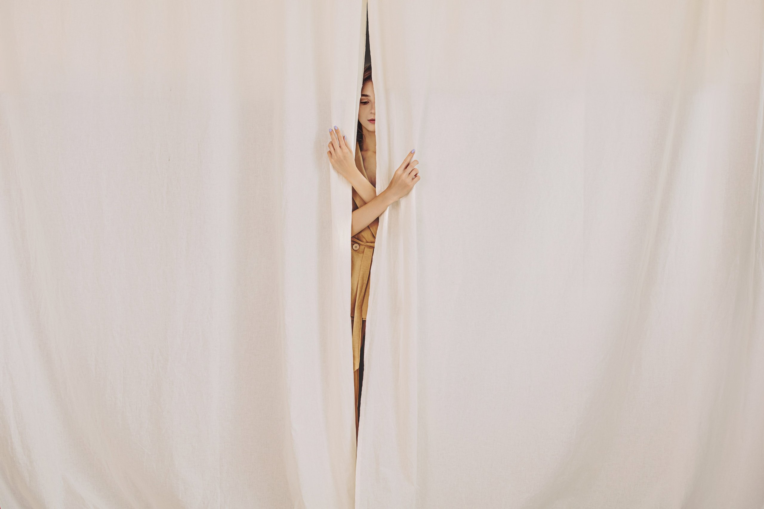 Main de femme entre des rideaux blancs – photo artistique et symbolique d’une séance portrait en studio
