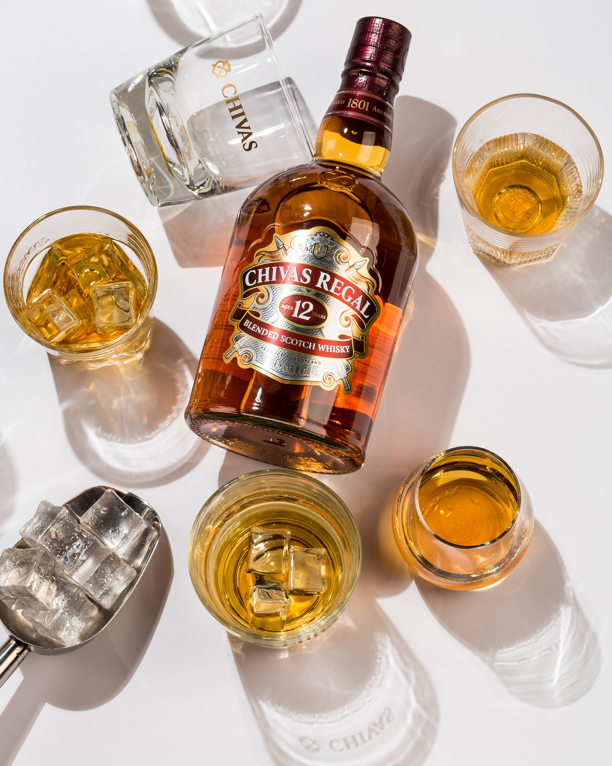 Chivas Regal 12 illik viski və buzlu qədəhlərdə təqdimat — lüks içki fotoqrafiyası.