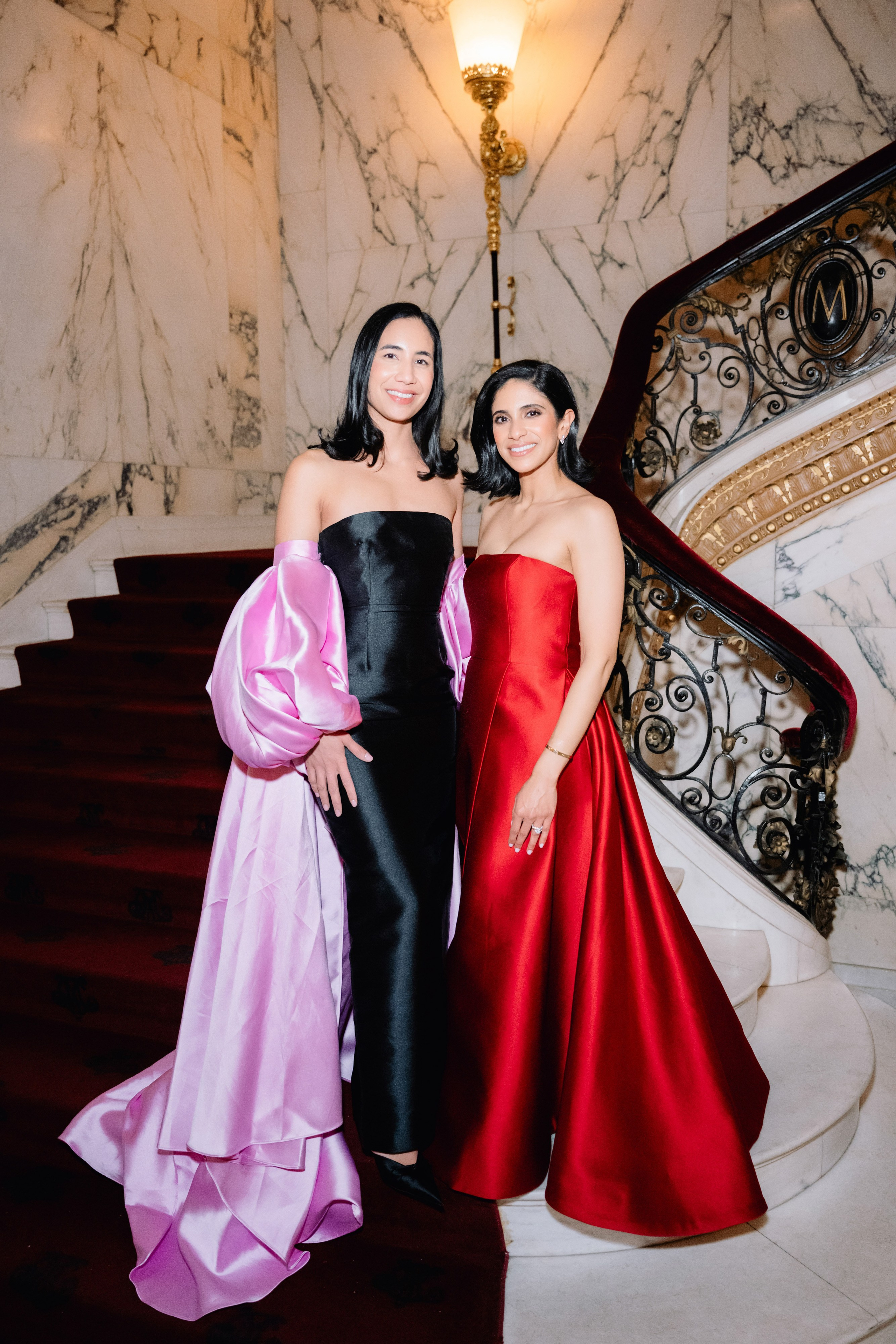 two women in red and black dresses standing on stairs