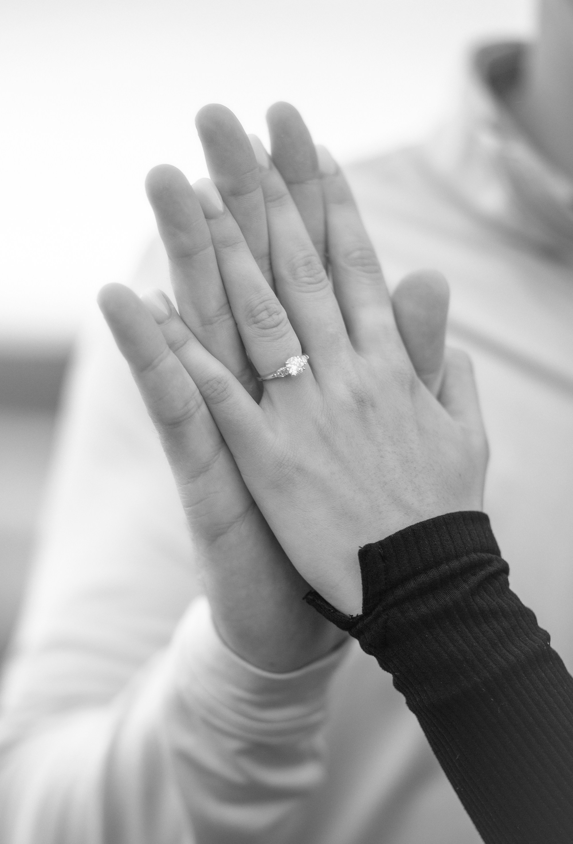 A close-up detail shot of the couple holding hands, highlighting an engagement ring against the natural landscape of Ireland.
