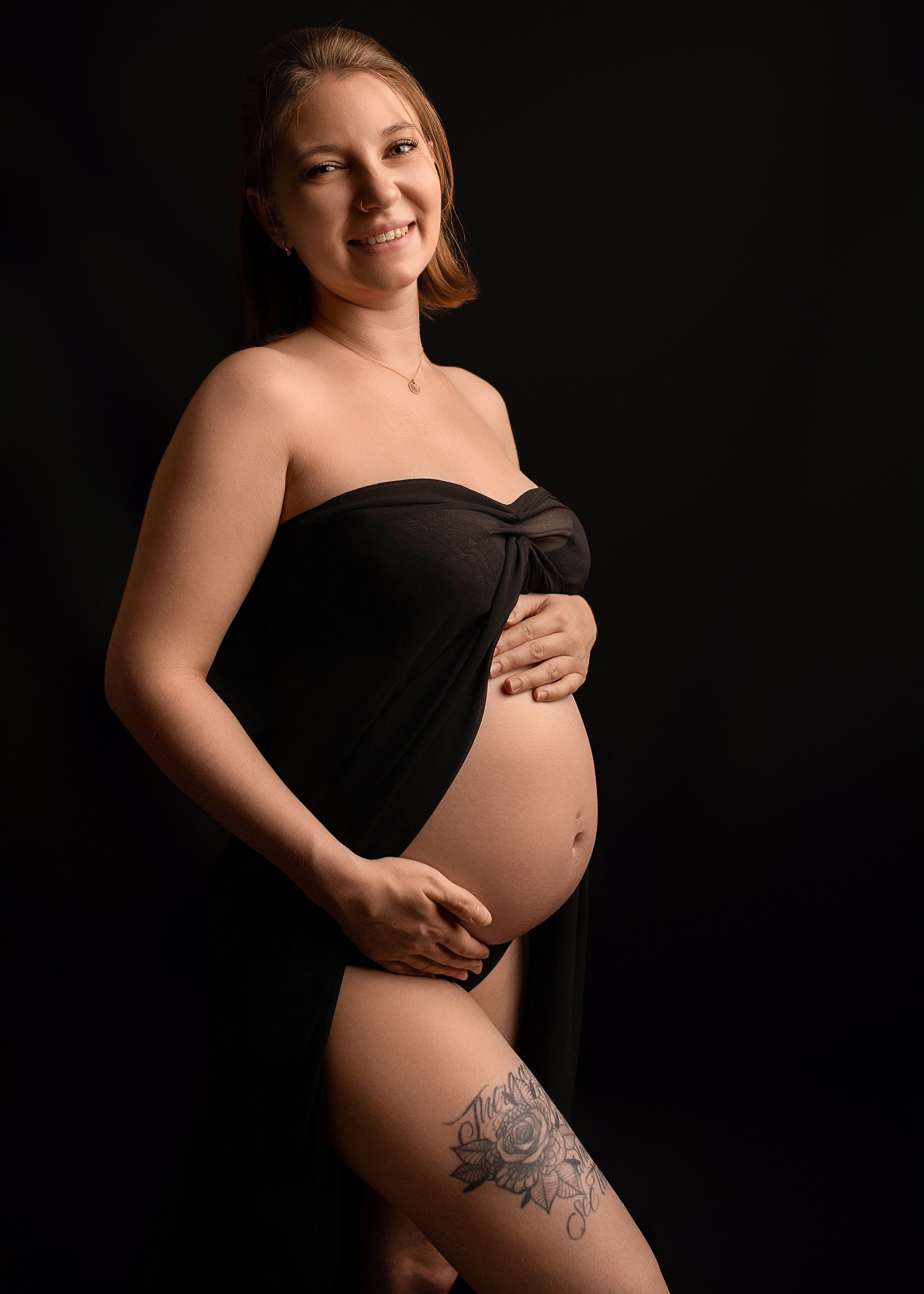 werdende Mama in schwarzem Tüllstoff hält Babybauch und lächelt - Schwangerschaftsfotografie Weißenhorn bei Ulm