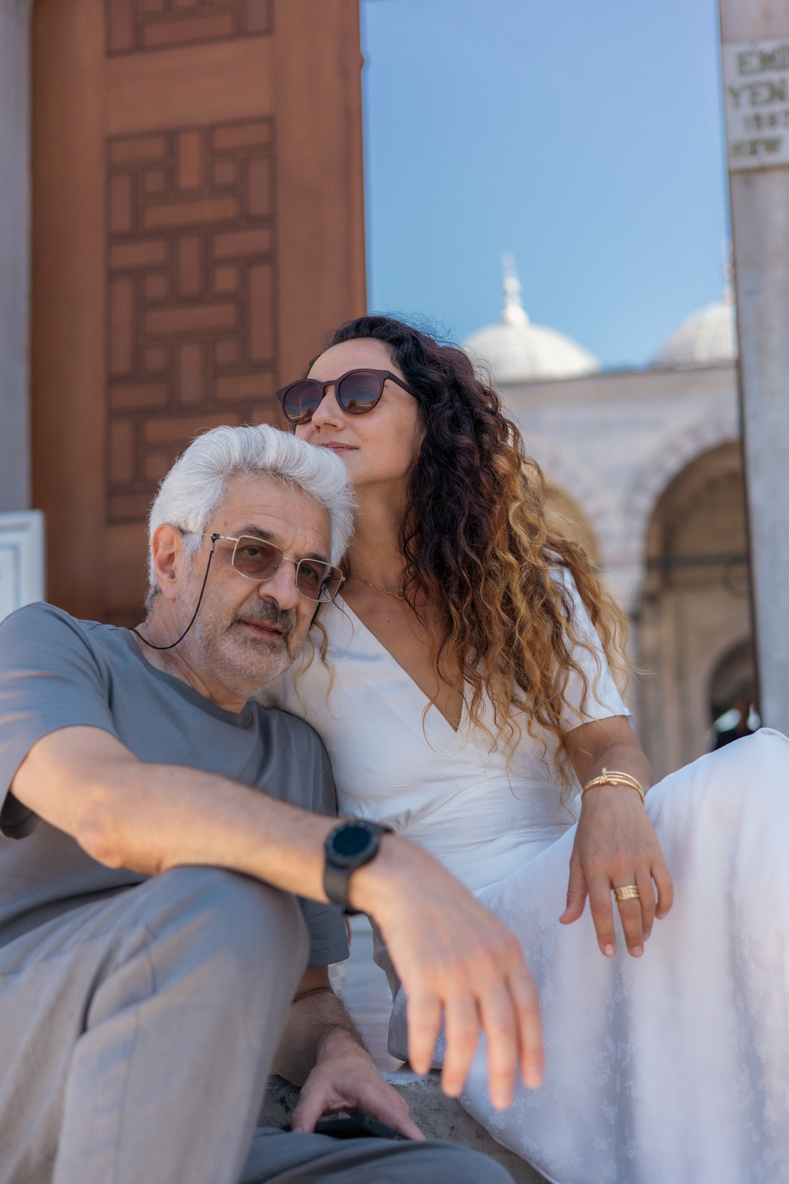 Фотопрогулка для пары в Стамбуле - пара сидит на ступеньках мечети 16 века на площади Эминоню