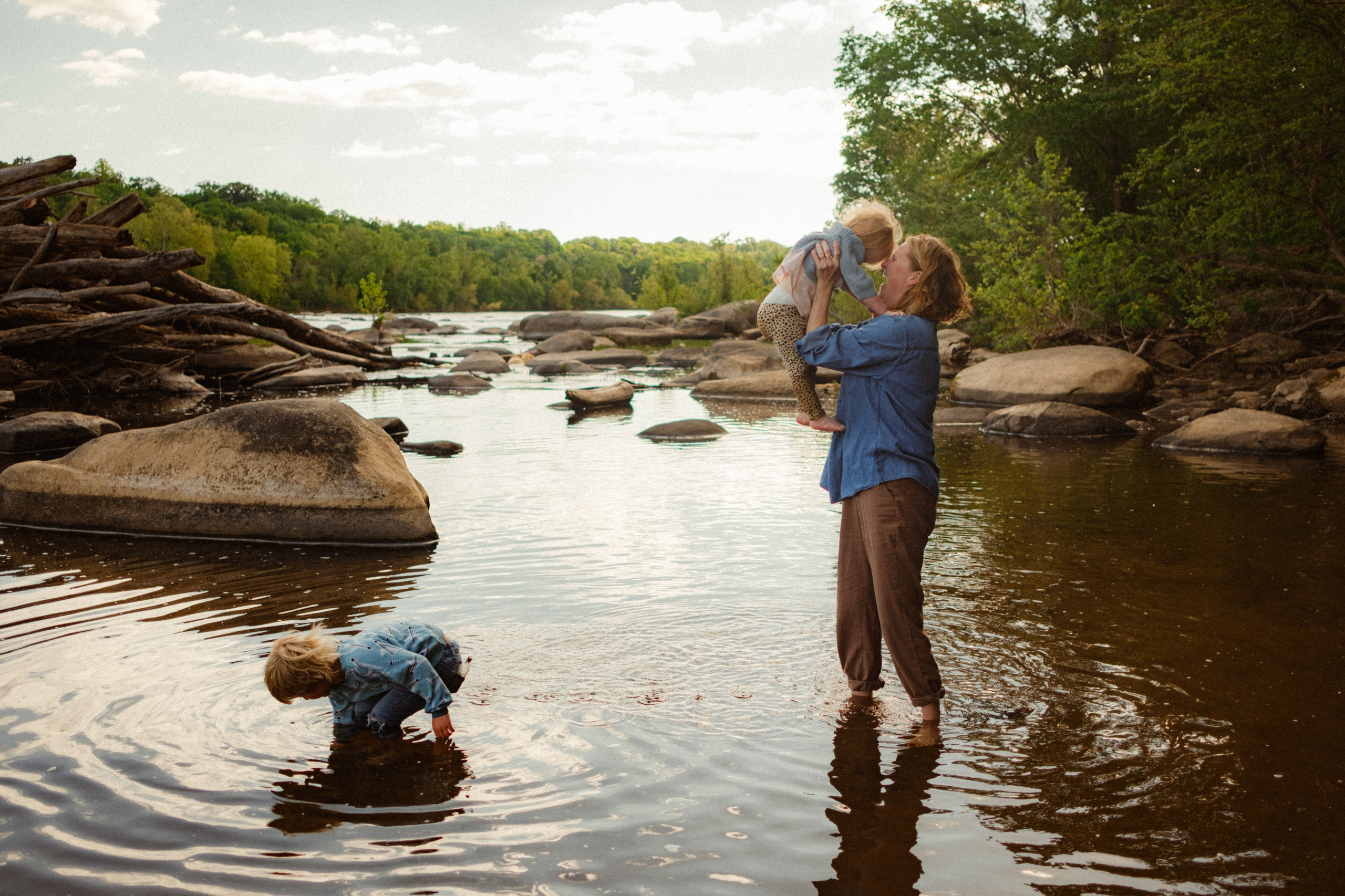 Artistic family photography playing with natural light and dramatic shadows on the river rocks at the James River