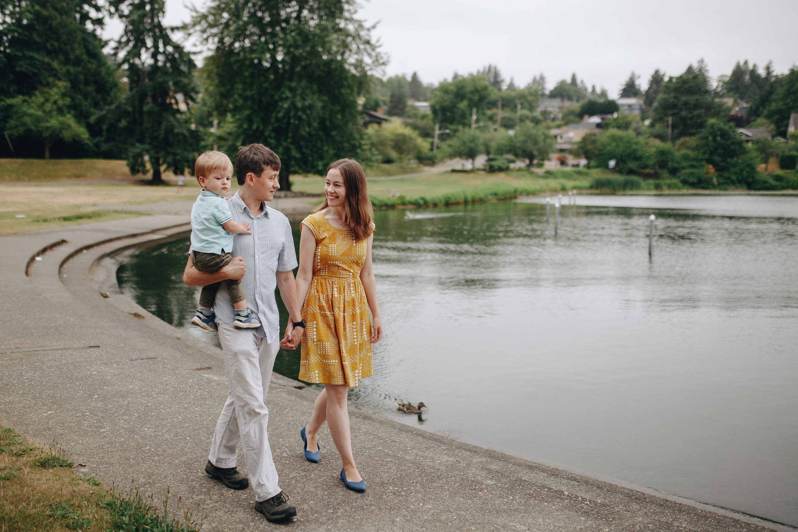 Mother, dad and child walking by lake, outdoor family moment